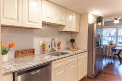 Cream-colored kitchen with white tile backsplash, stainless steel appliances, and granite countertops. Dining area visible.
