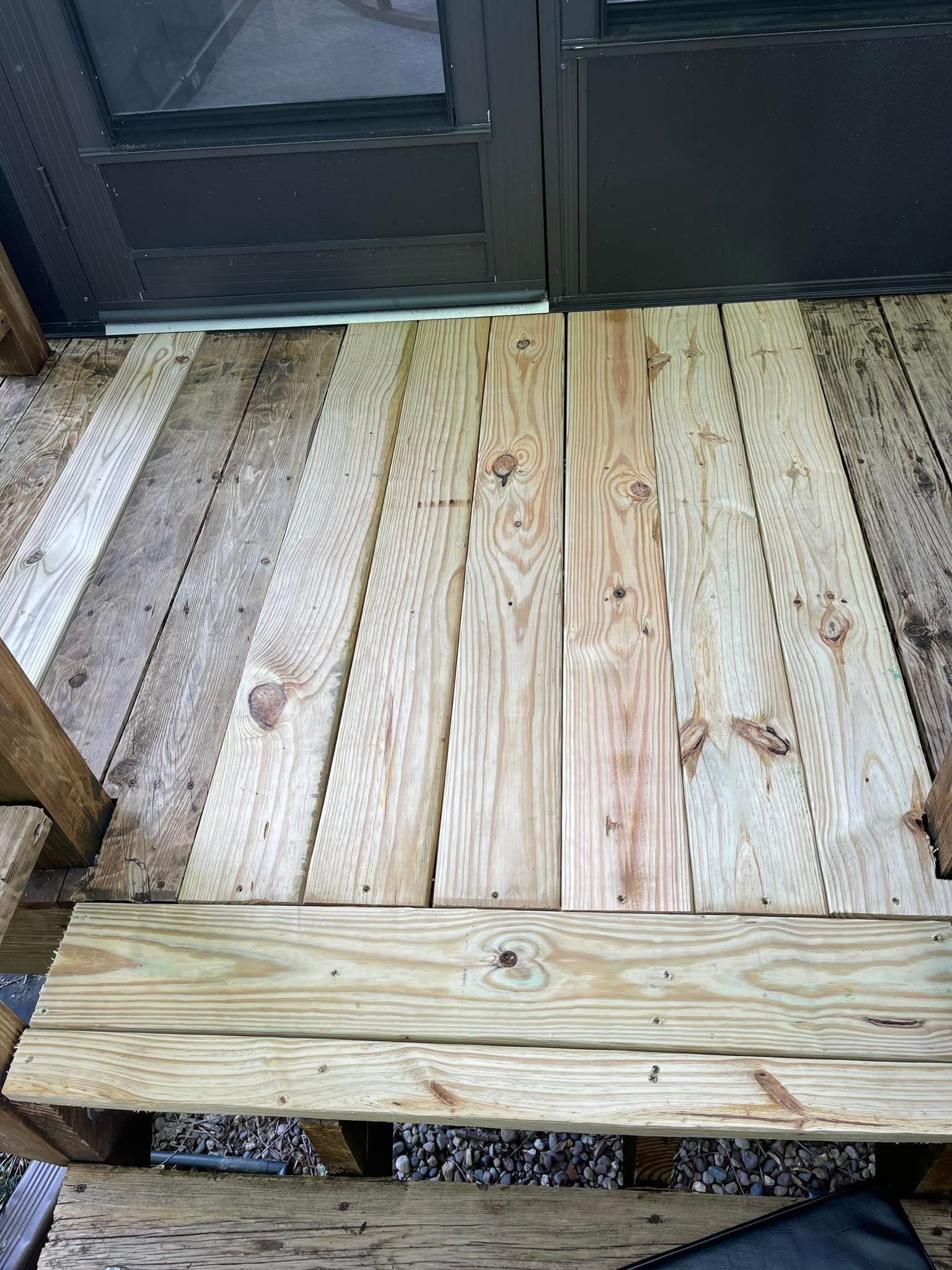 Wooden deck with angled planks, leading to a dark structure; some planks are weathered.