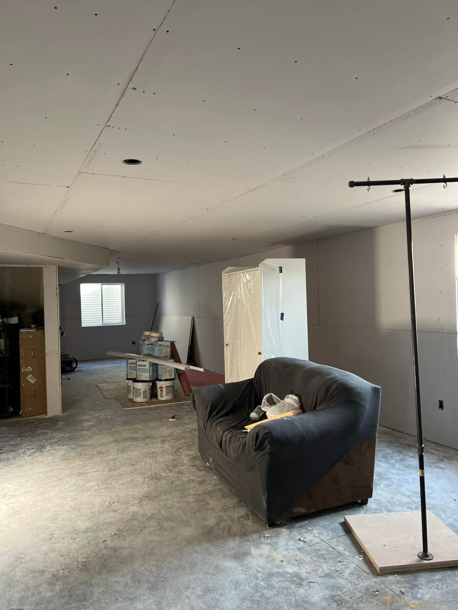Unfinished basement with drywall, couch, and construction materials.