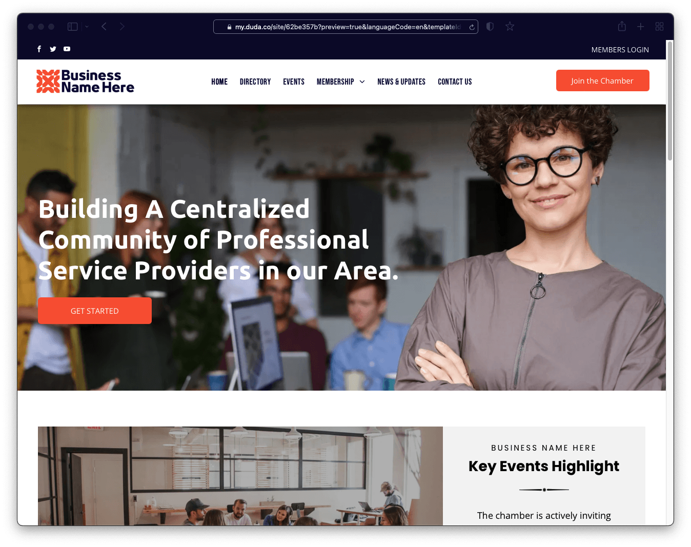 A woman wearing glasses is standing in front of a group of people.