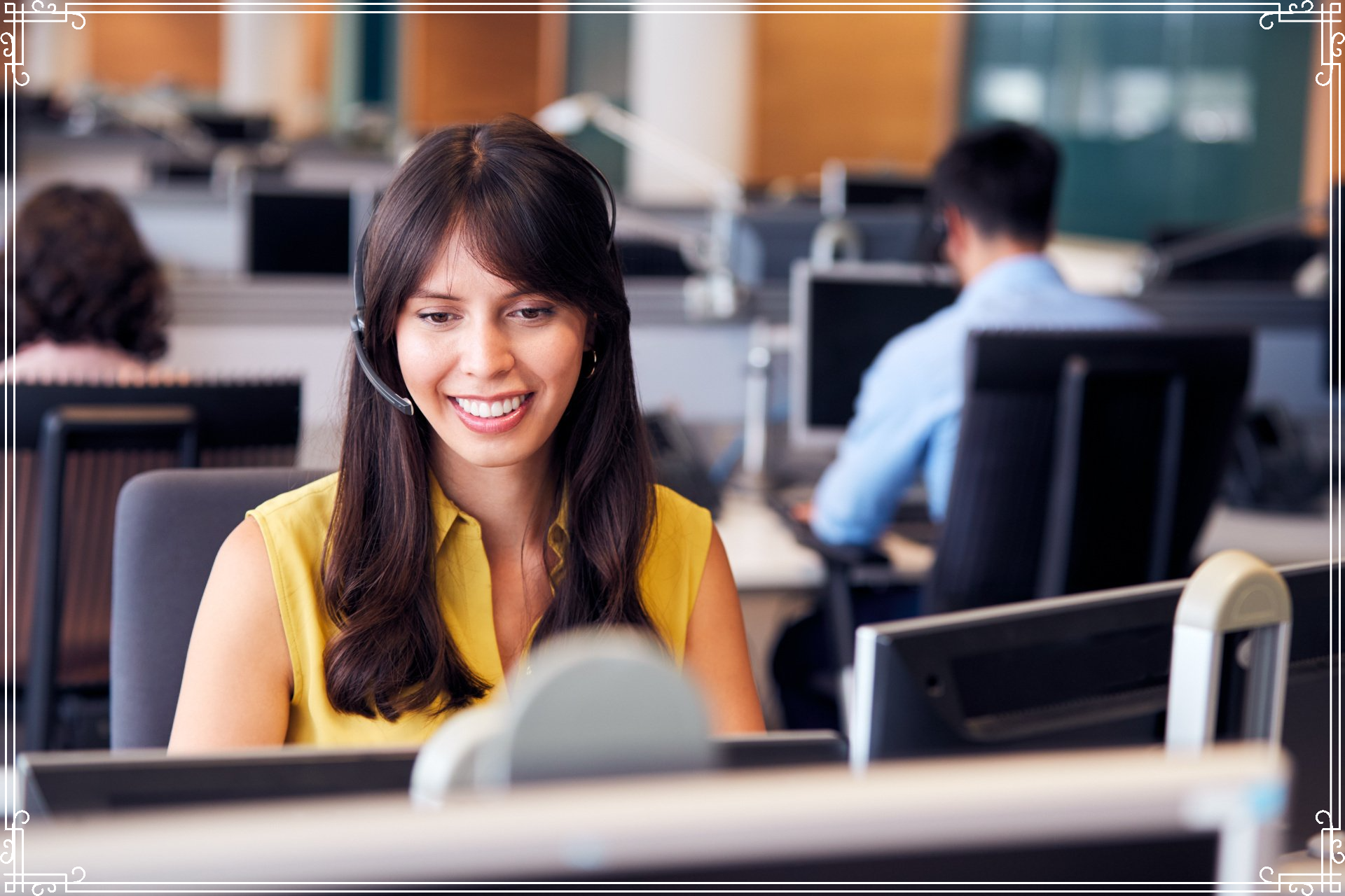 A woman wearing a headset is sitting at a desk in an office.