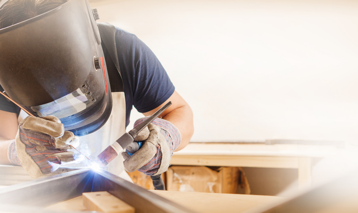 Welder in protective gear working on metal, bright sparks flying in a workshop