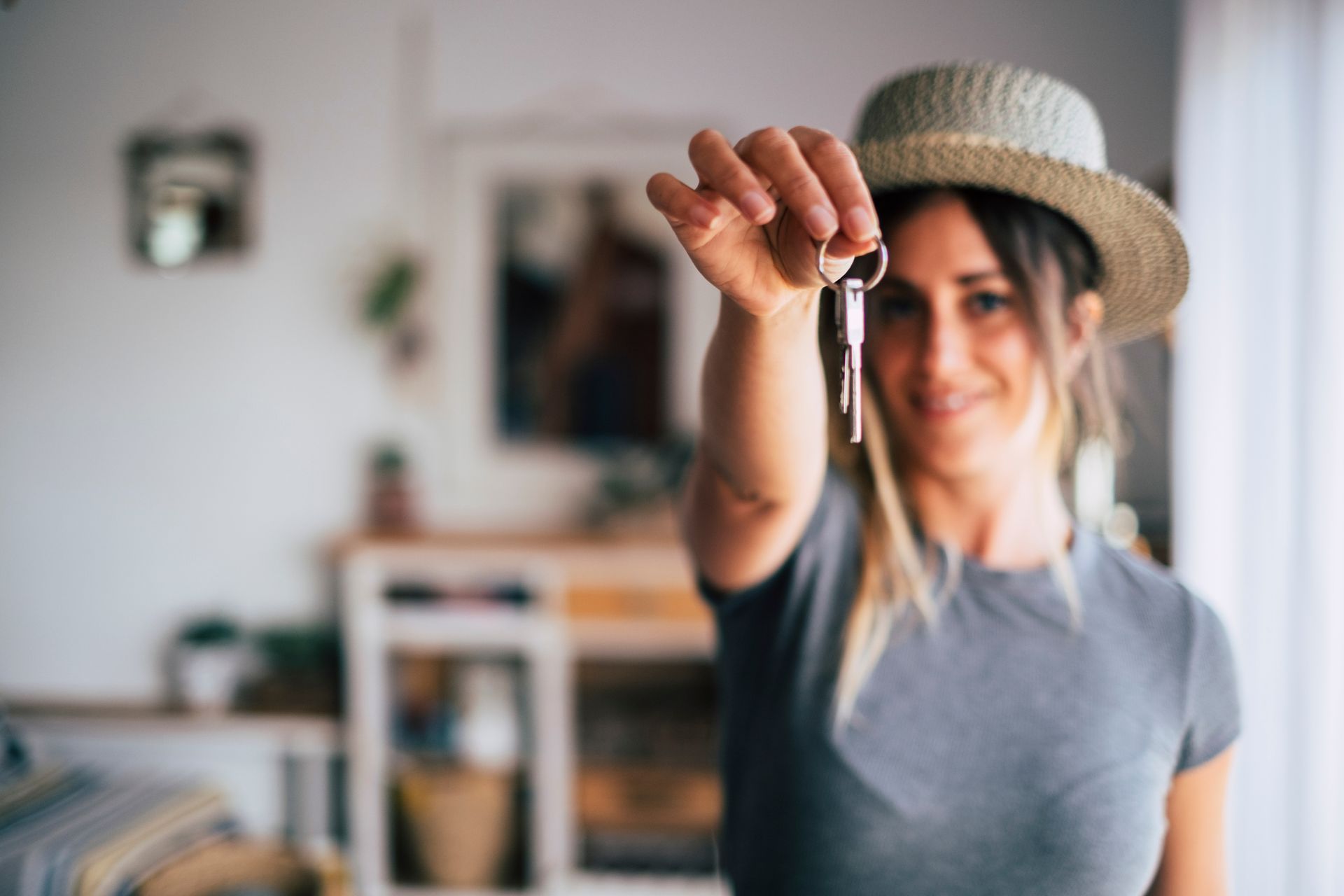 Close-up of a pair of keys being held by a young woman, smiling to the camera.