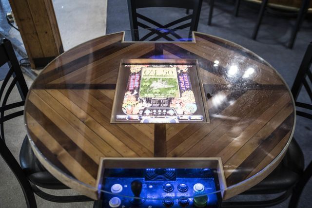 Wooden table with a built-in arcade game display. Players' control panel is beneath the screen.