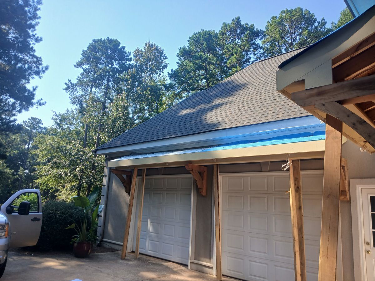 Garage under construction with two white doors, wooden supports, and blue roofing material.