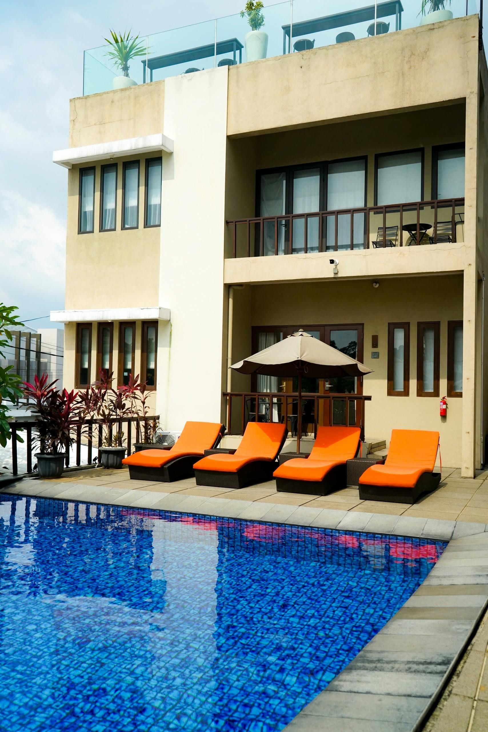 Swimming pool with orange lounge chairs, and a multi-story building.