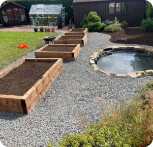 Raised garden beds with gravel path and pond in backyard.