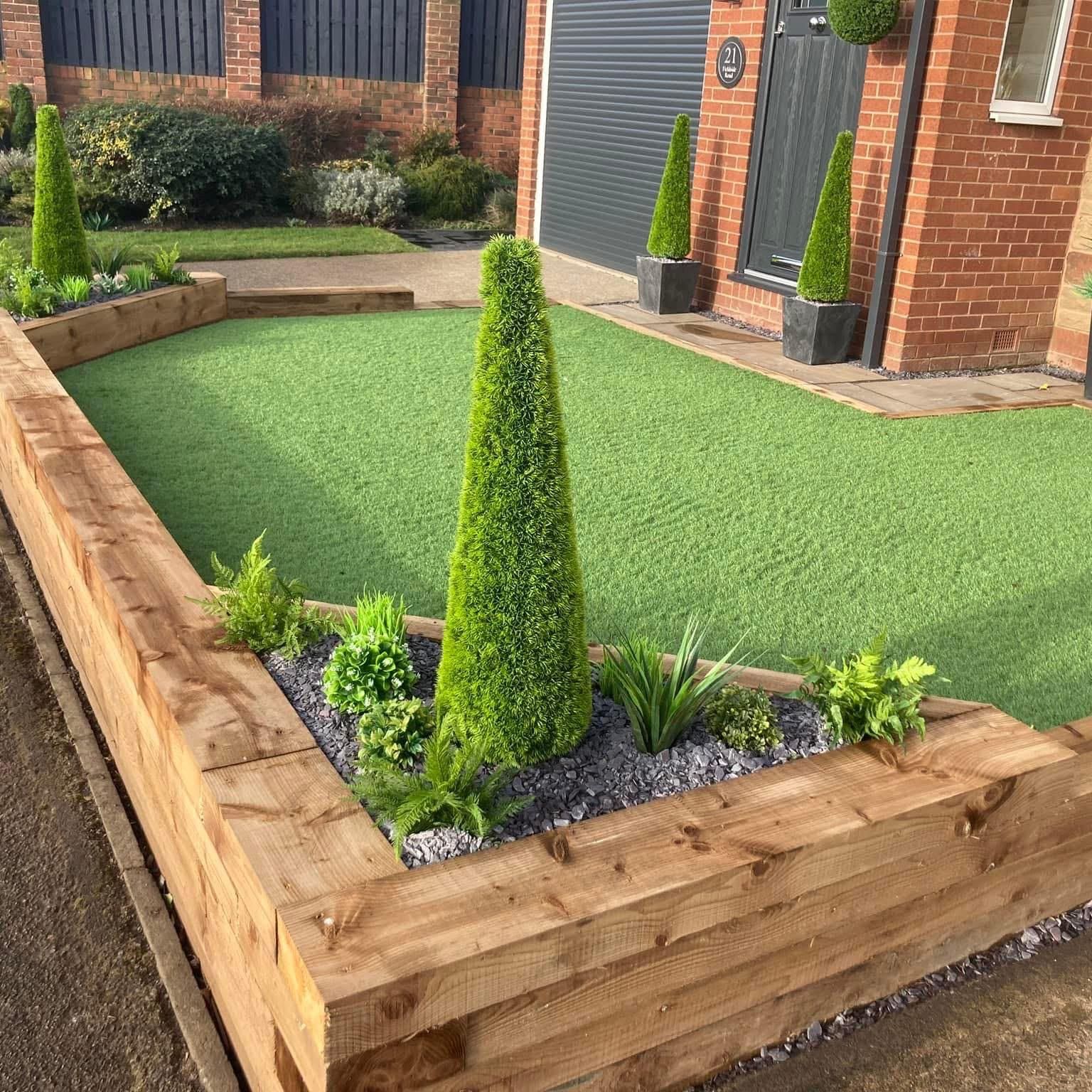 Front yard with wooden planters, artificial green turf, and cone-shaped topiary trees.