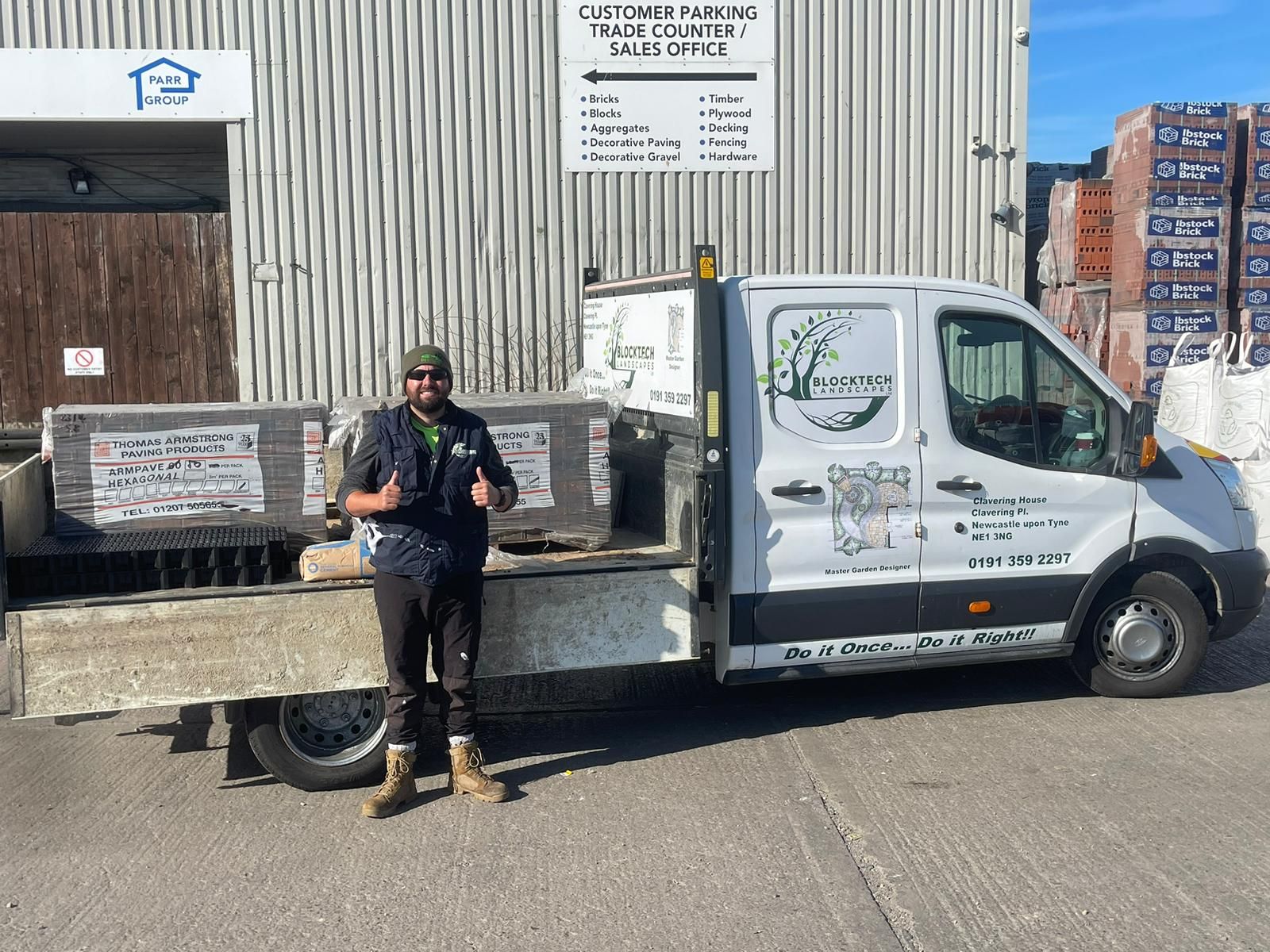 Person standing beside a white utility truck in front of a warehouse loading dock