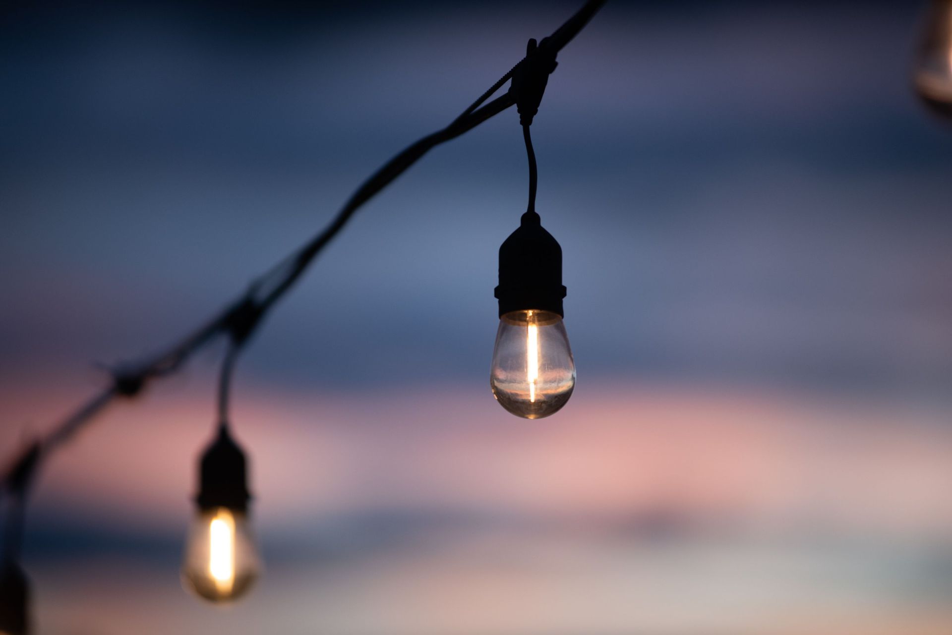 String lights glowing at dusk against a blurred blue and pink sky