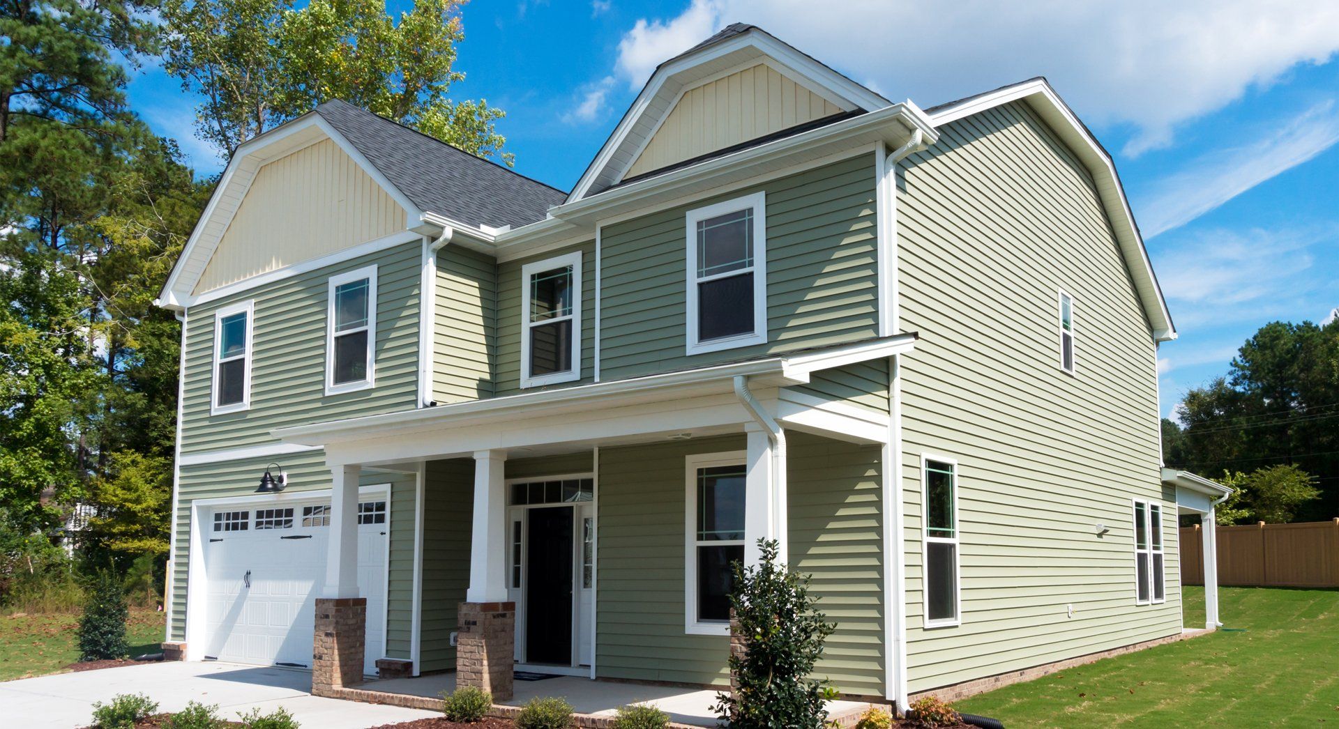 A green and white house with a garage and a porch