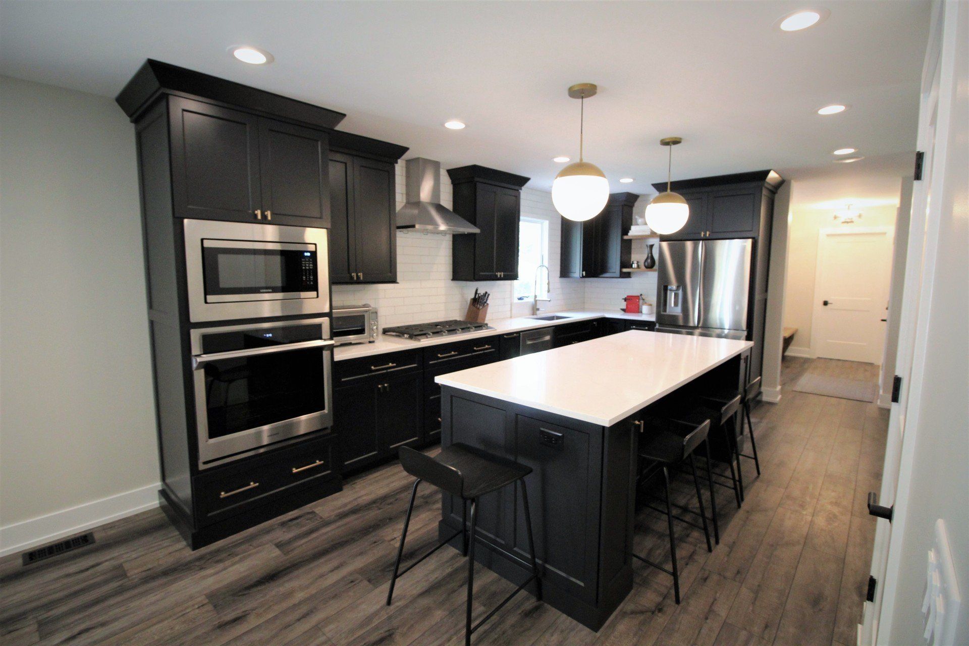 A kitchen with black cabinets , stainless steel appliances , and a large island.