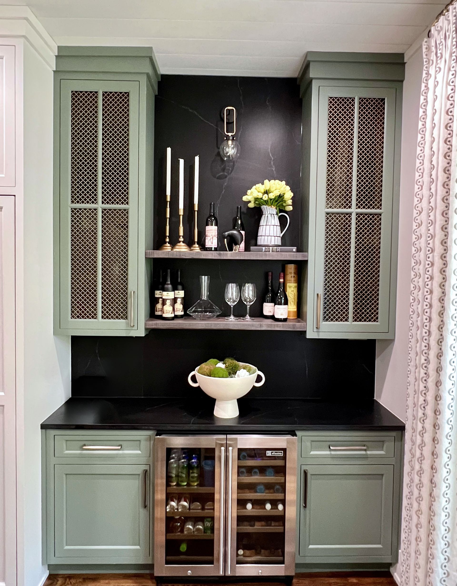 A kitchen with green cabinets and a wine cooler