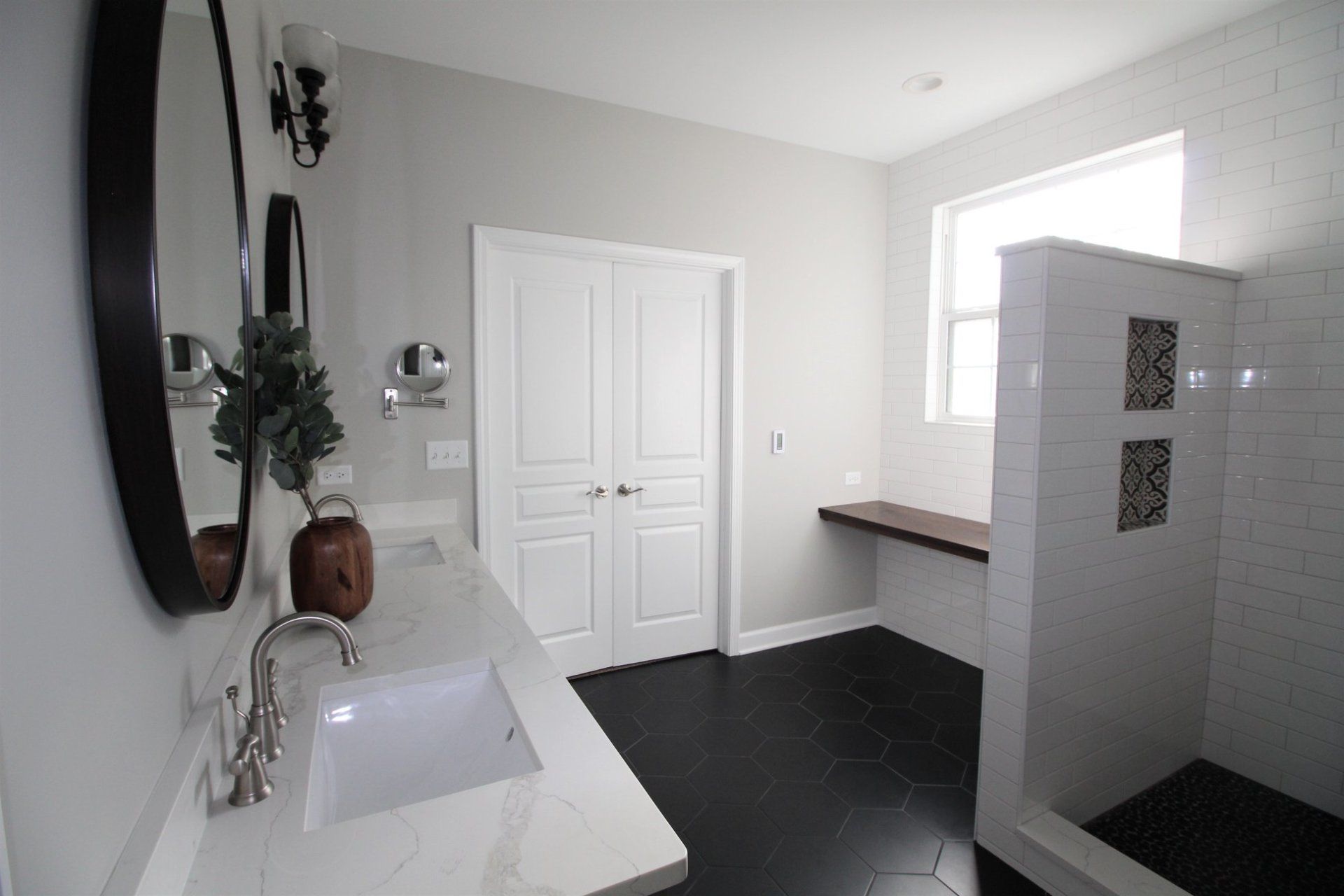 A bathroom with a sink , mirror , and walk in shower.
