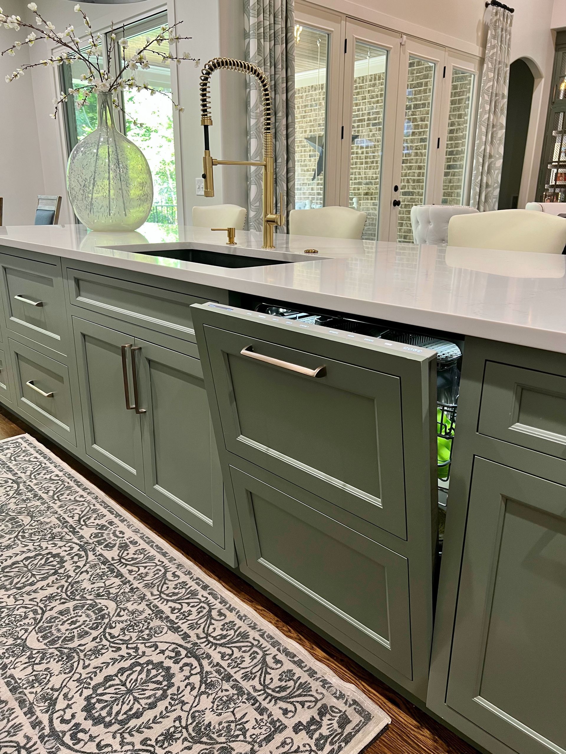 A kitchen with green cabinets and a rug on the floor