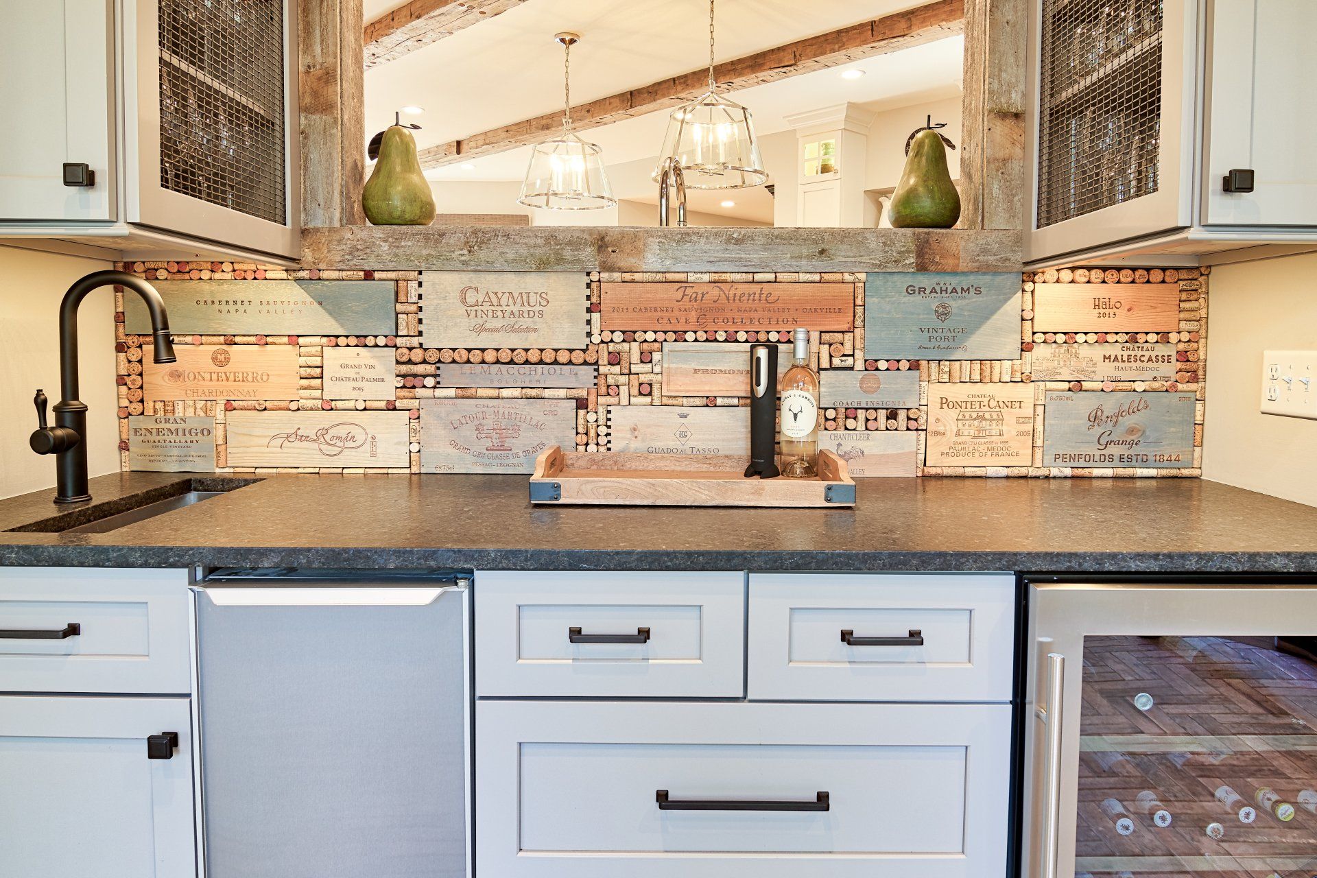 A kitchen with white cabinets , black counter tops , a sink and a refrigerator.