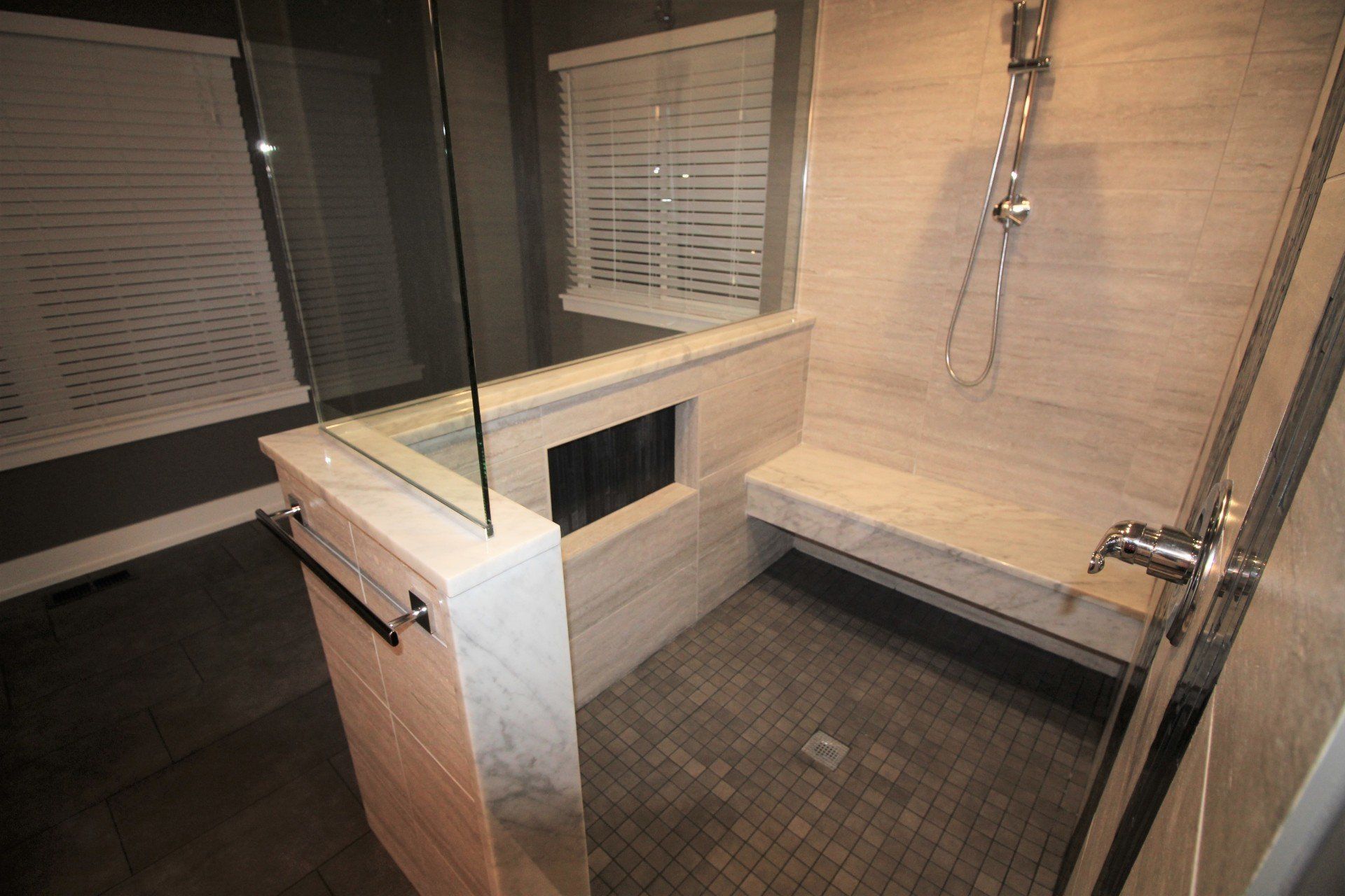 A bathroom with a walk in shower and a bench