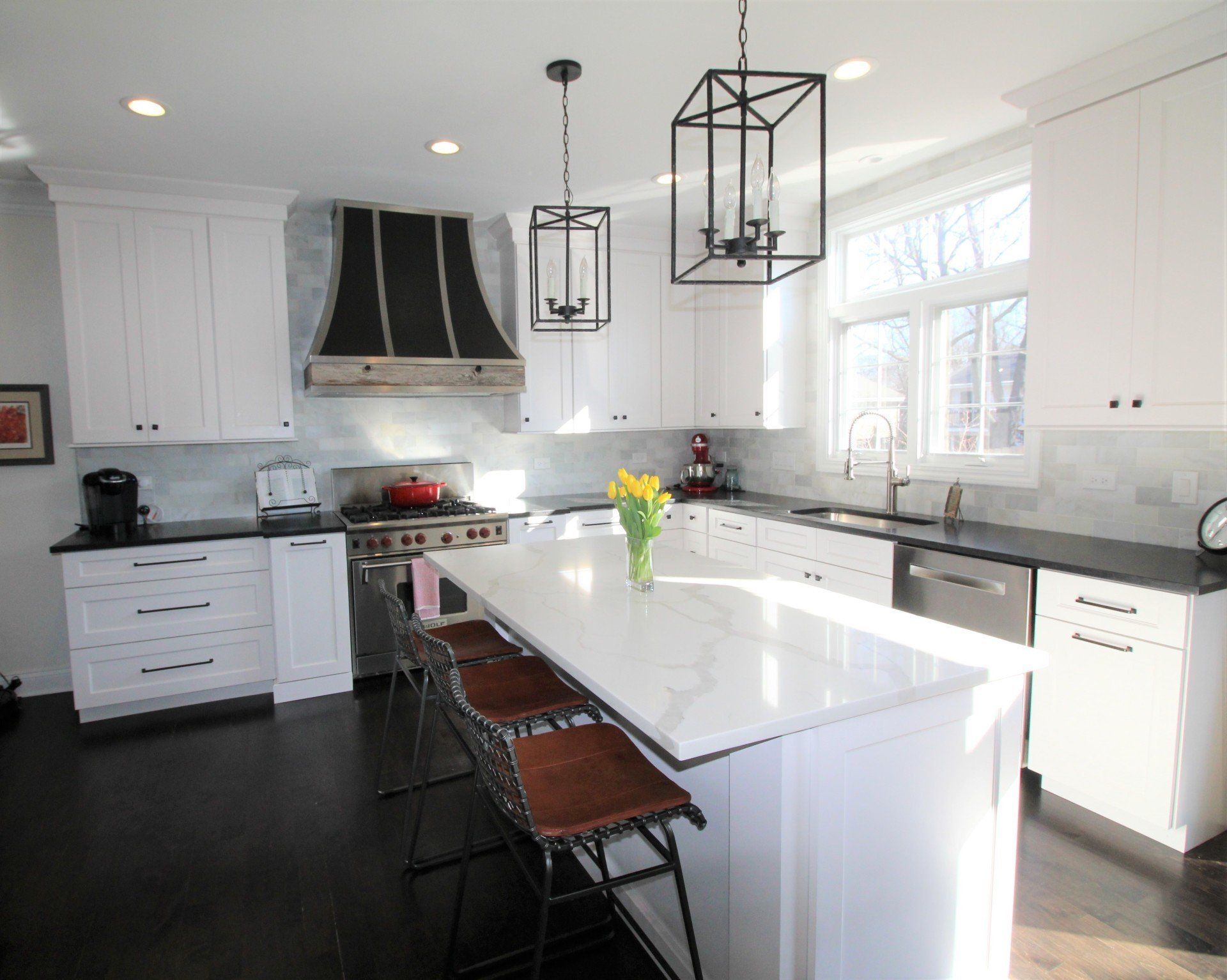 A kitchen with white cabinets and black counter tops