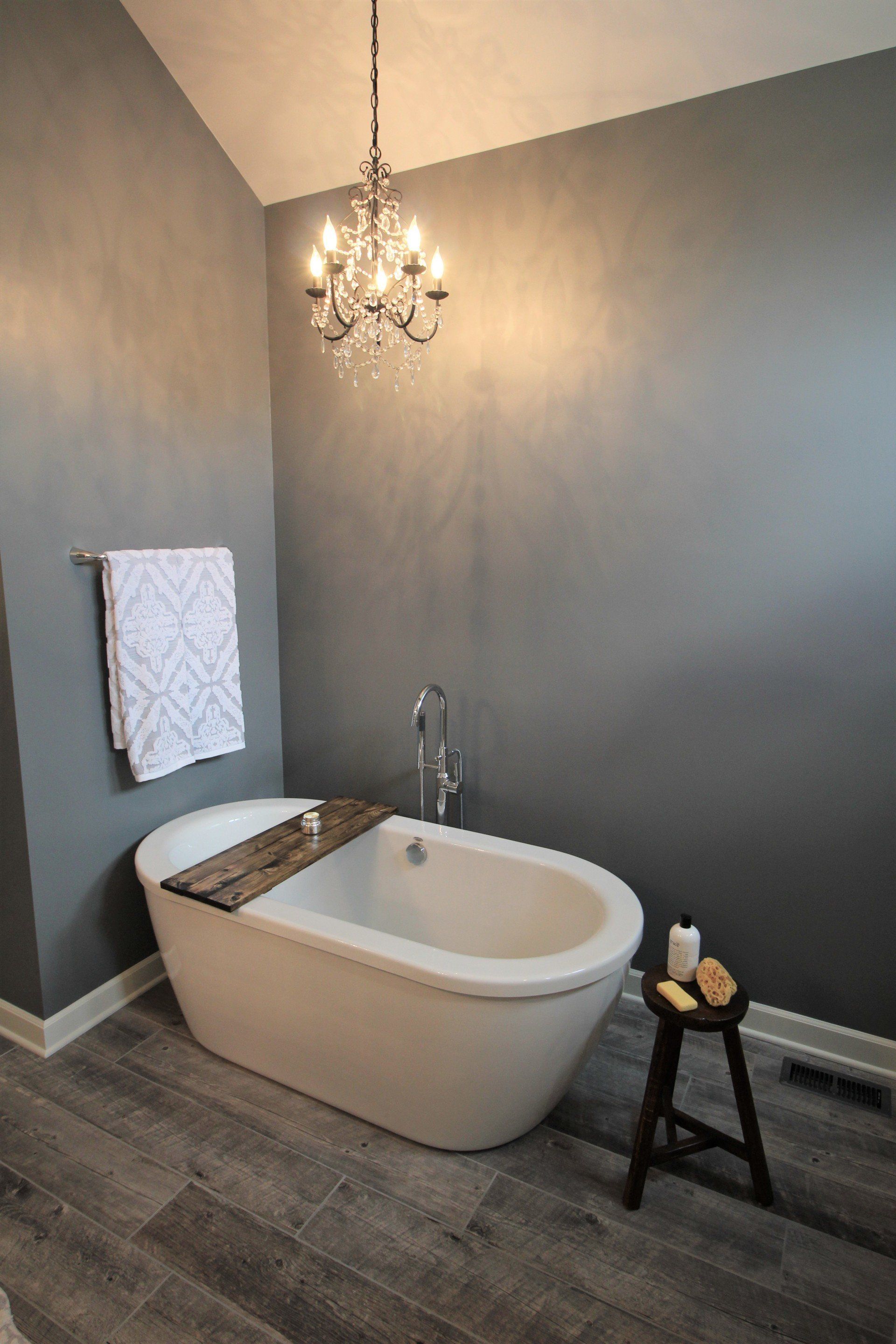 A bathroom with a bathtub and a chandelier hanging from the ceiling.