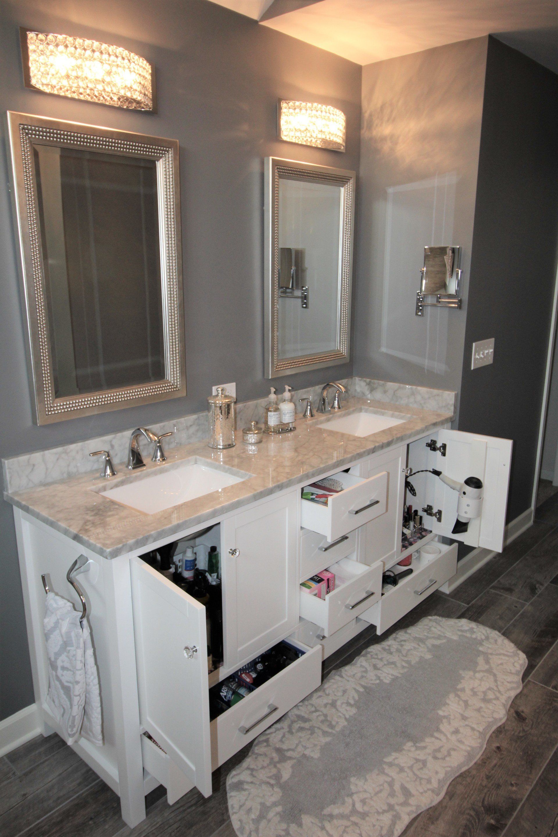 A bathroom with two sinks and two mirrors with drawers open