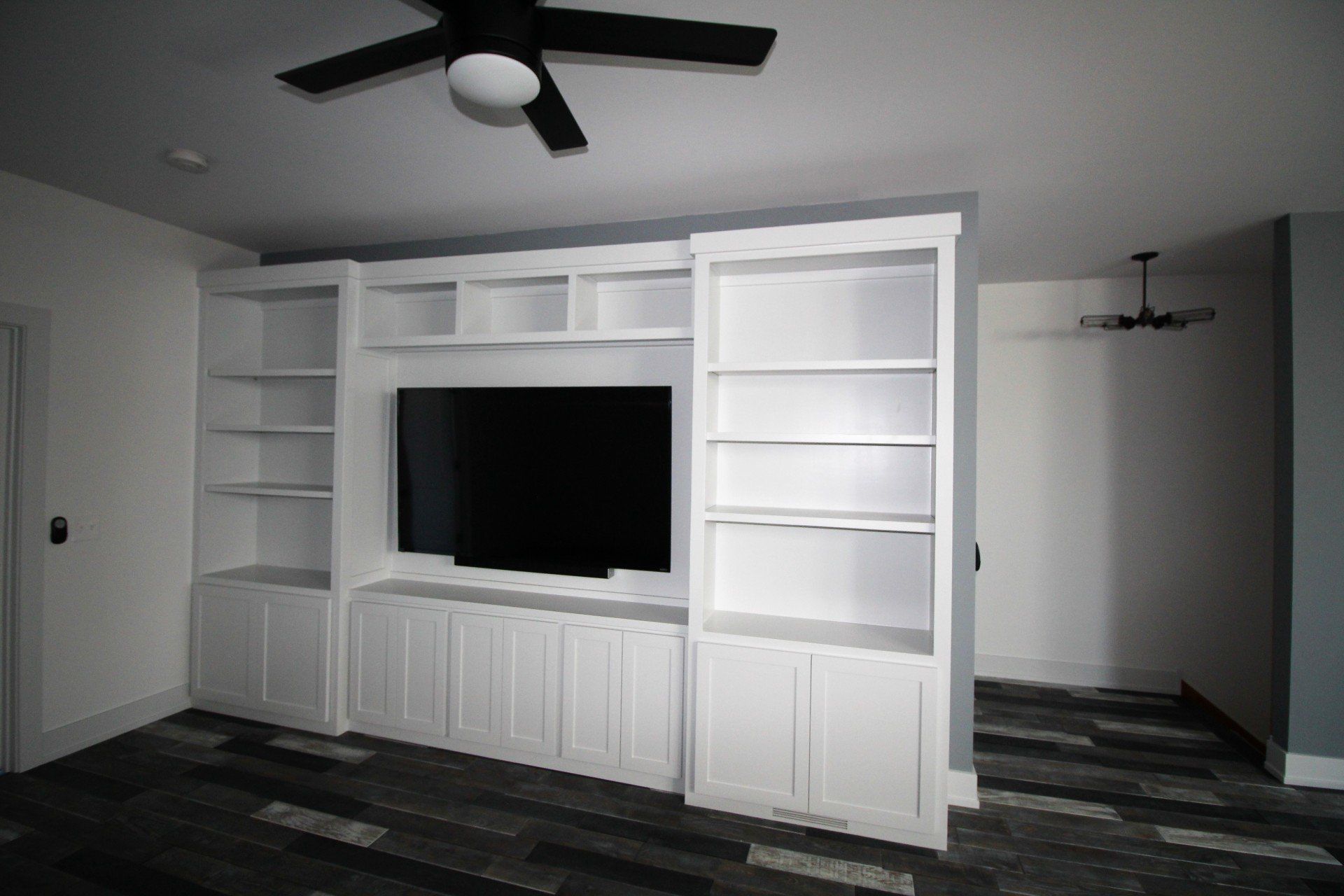 A large entertainment center with a flat screen tv and a ceiling fan.