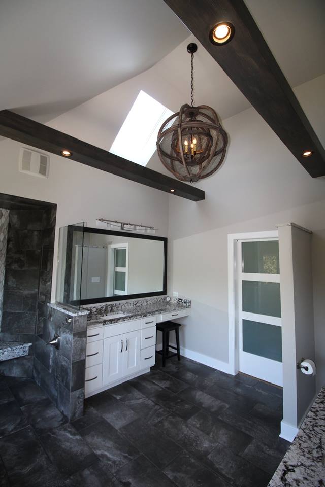 A bathroom with a large mirror and a chandelier hanging from the ceiling.