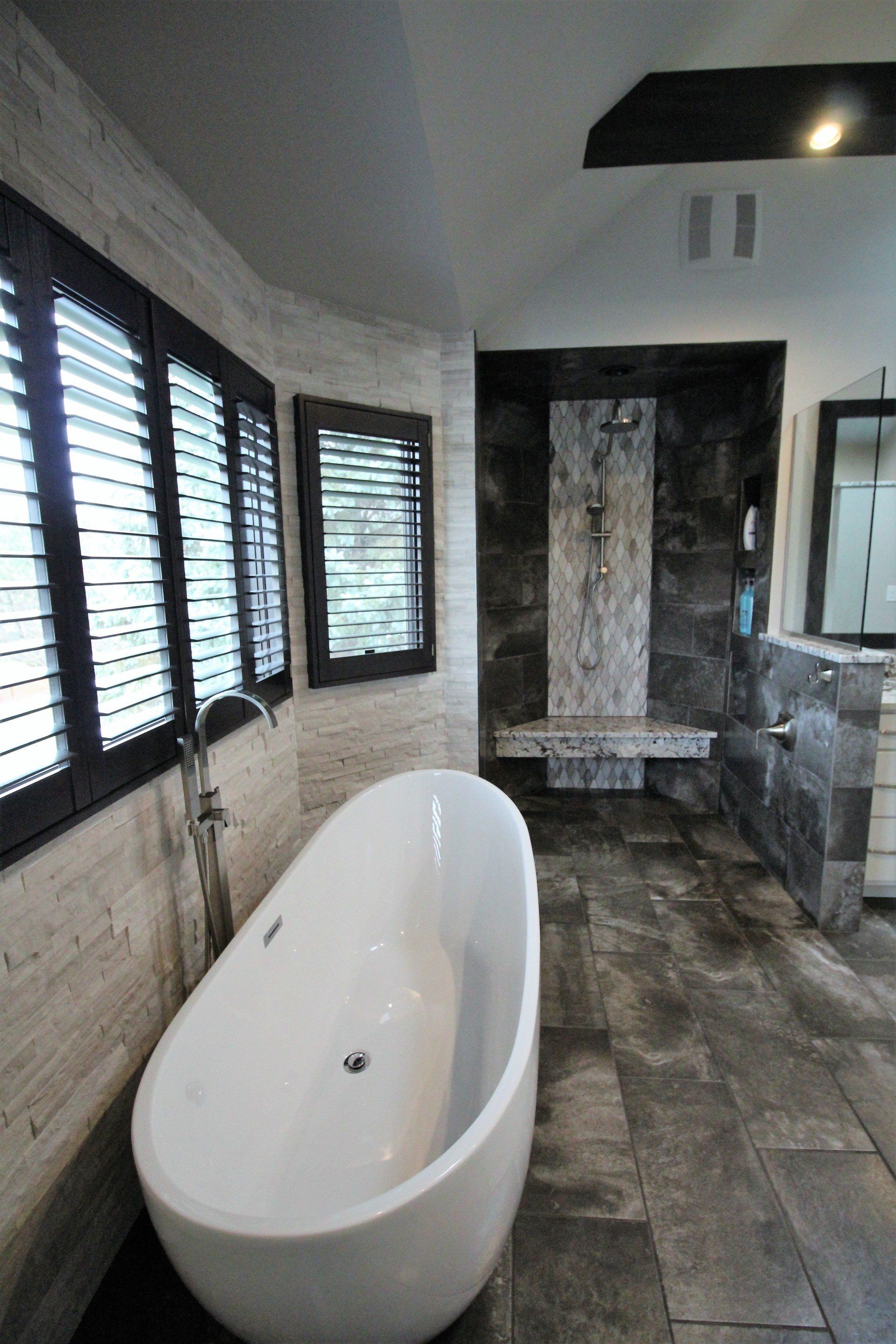 A bathroom with a bathtub and shutters on the windows