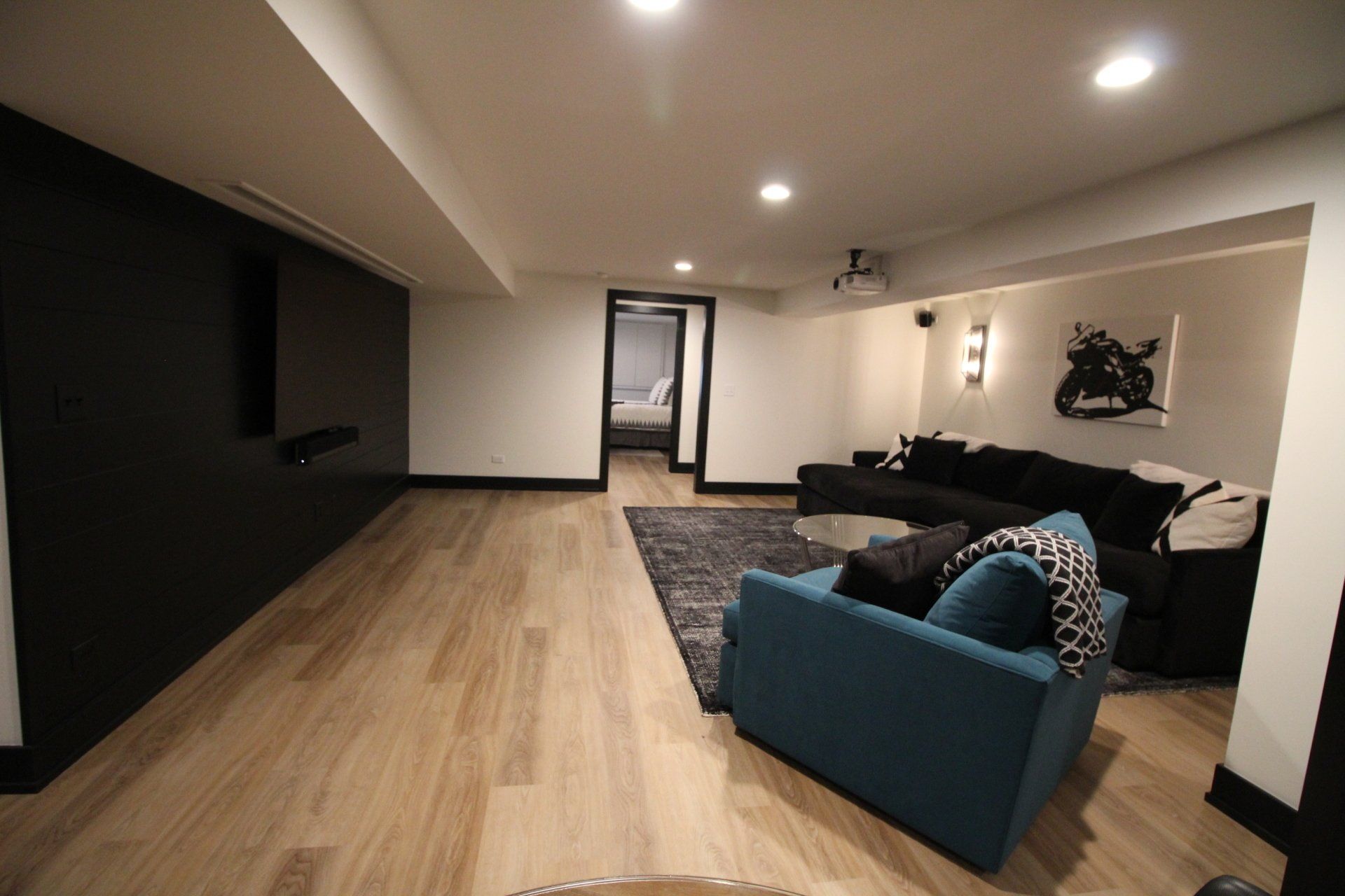 A living room with a blue couch and a black couch.