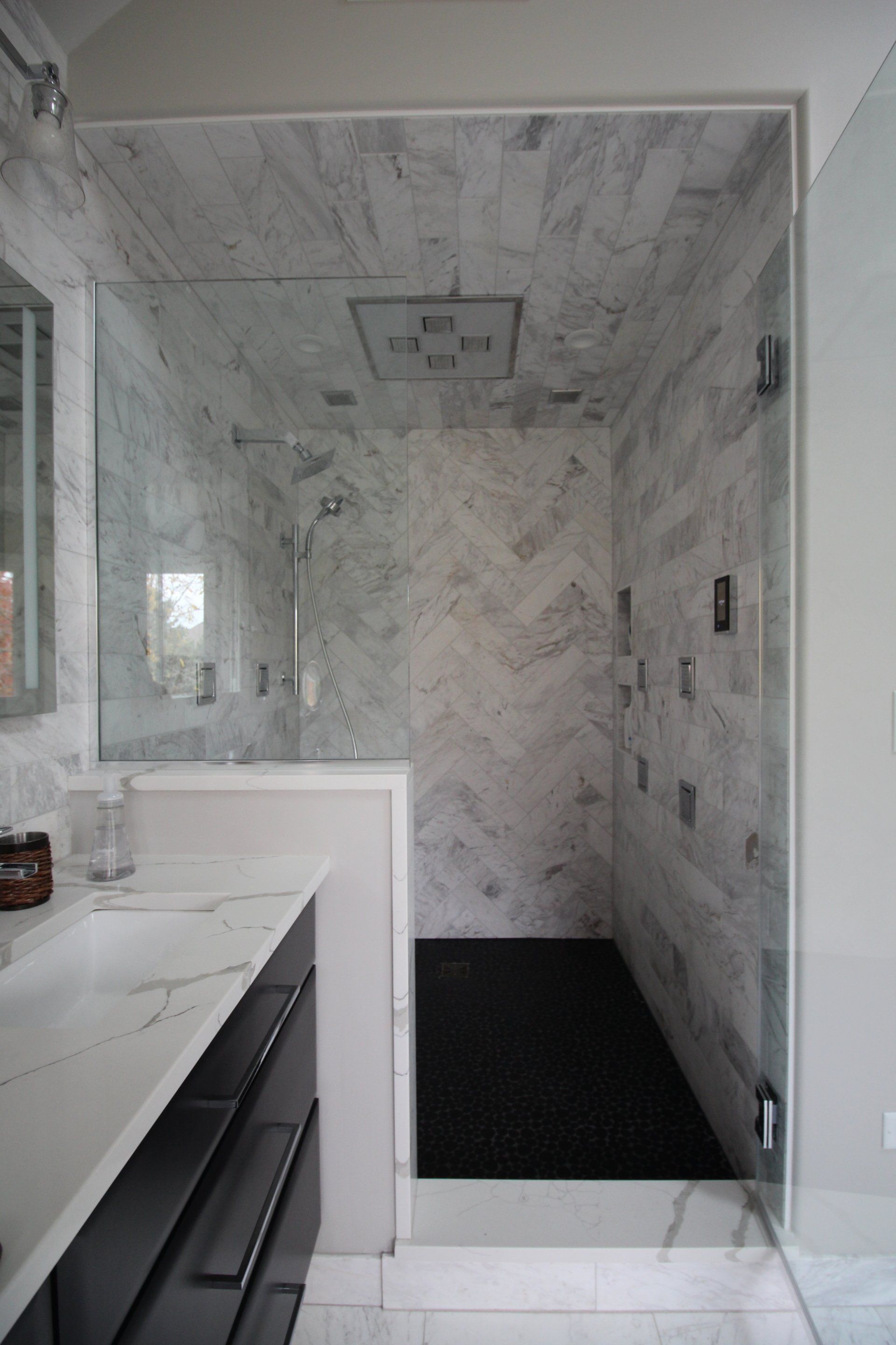 A bathroom with a walk in shower and a sink.
