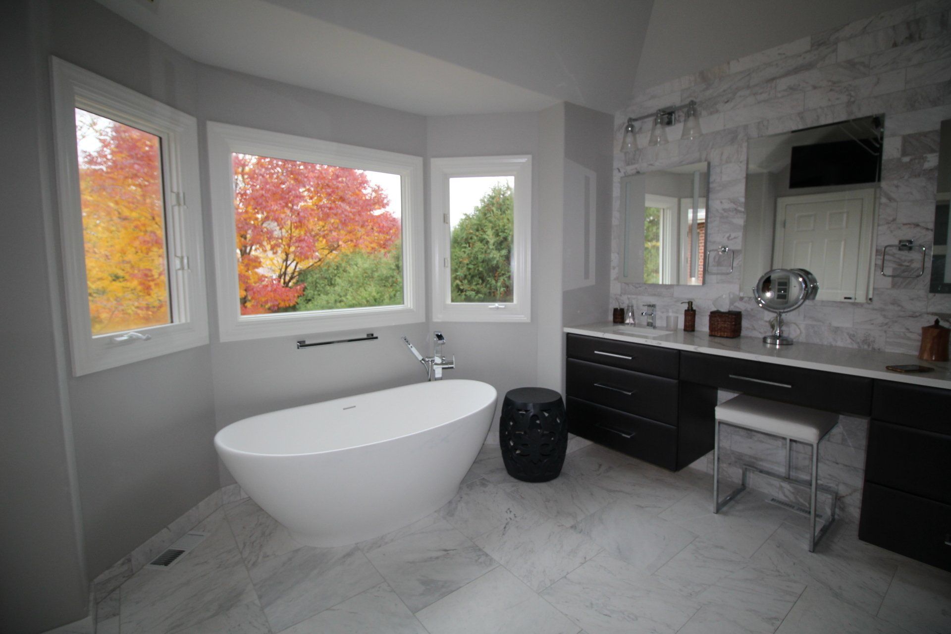 A bathroom with a bathtub , sinks , and a large window.