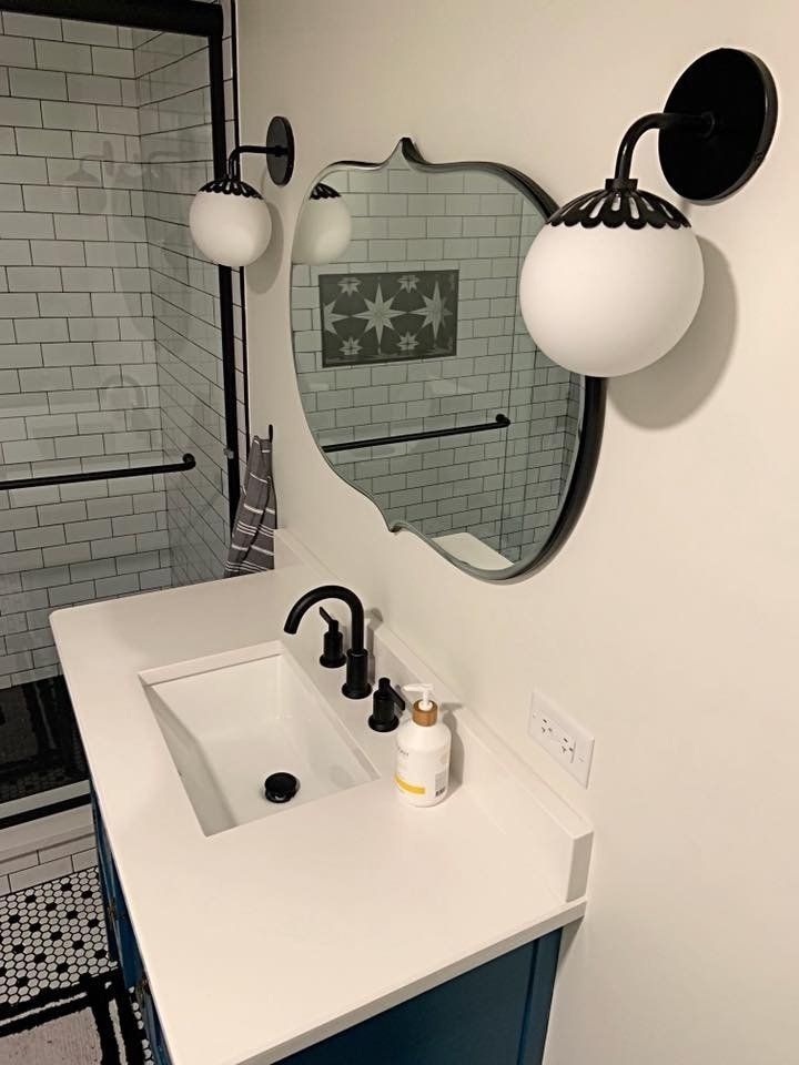 A bathroom with a sink , mirror and soap dispenser.