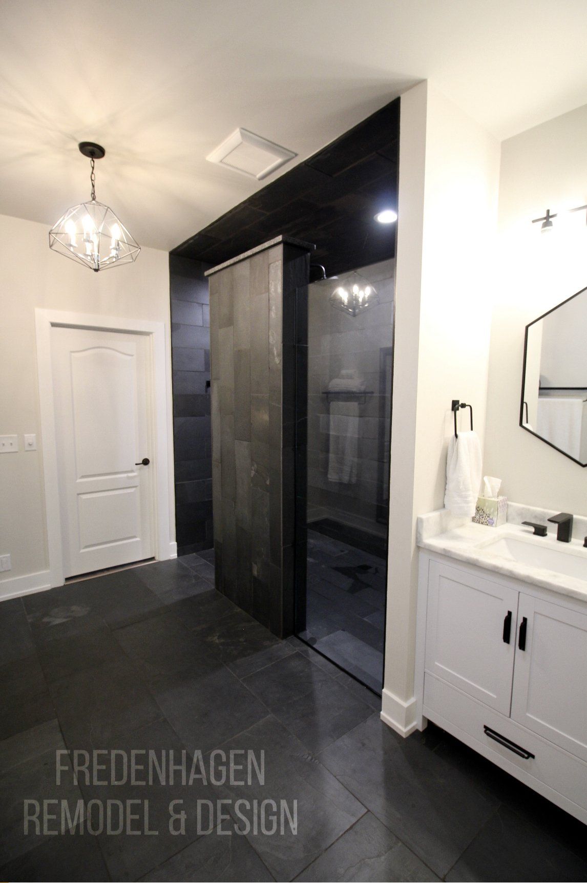 A bathroom with a sink , mirror and walk in shower.