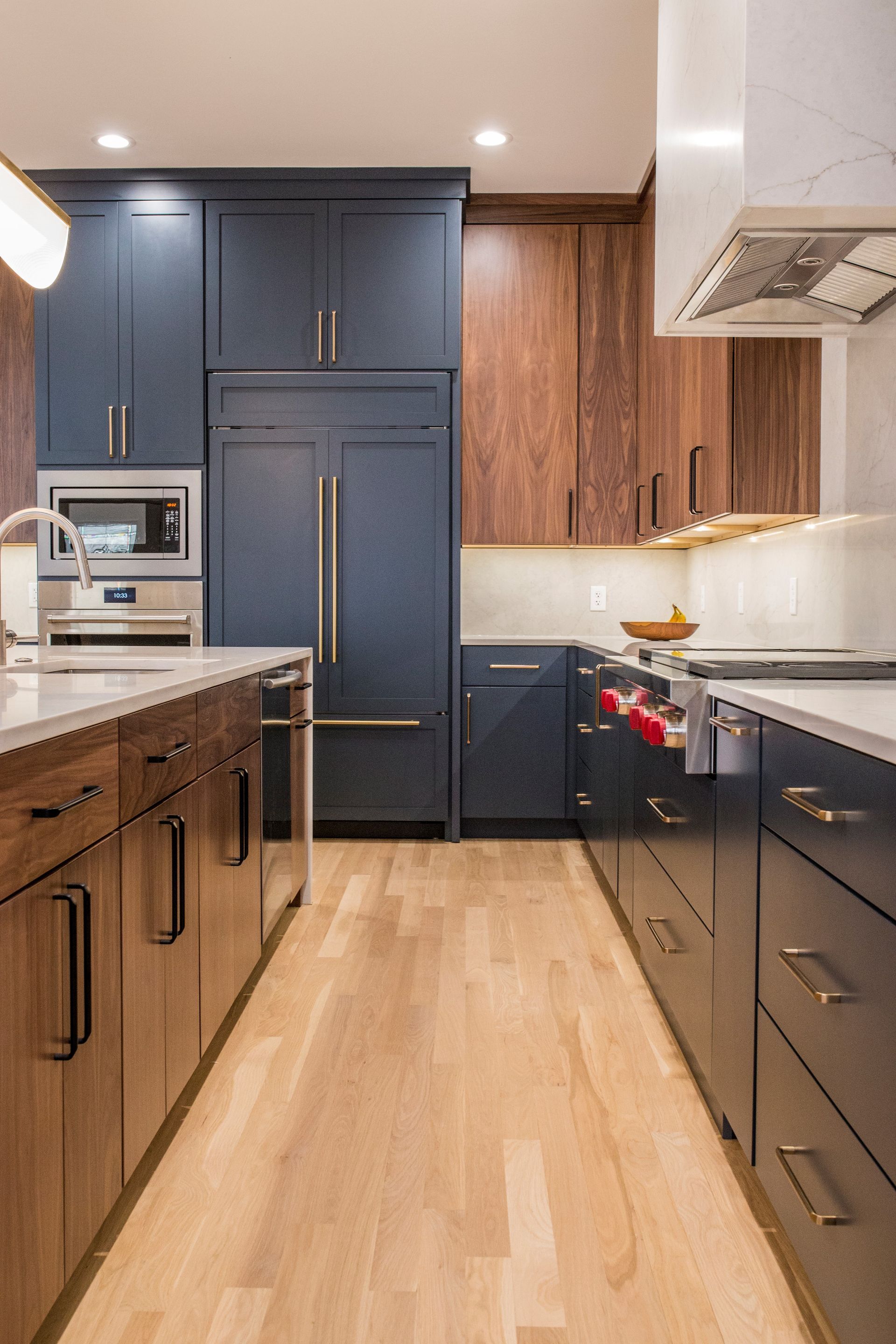 A kitchen with blue cabinets , wooden cabinets , and stainless steel appliances.