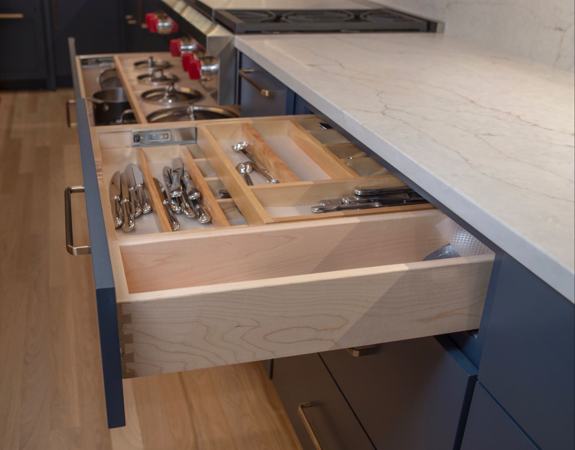 A kitchen drawer filled with silverware and pots and pans