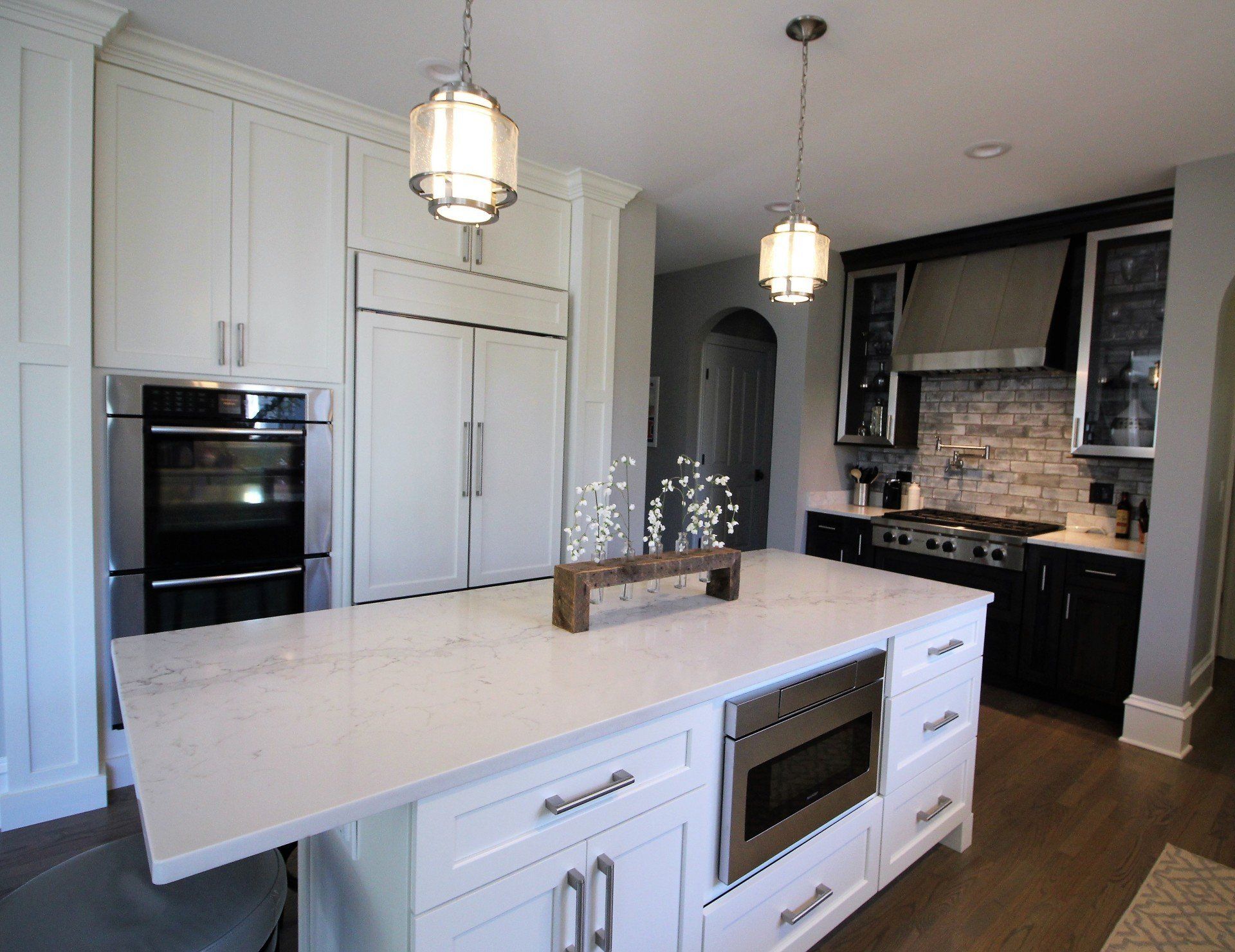 A kitchen with white cabinets , stainless steel appliances , and a large island.