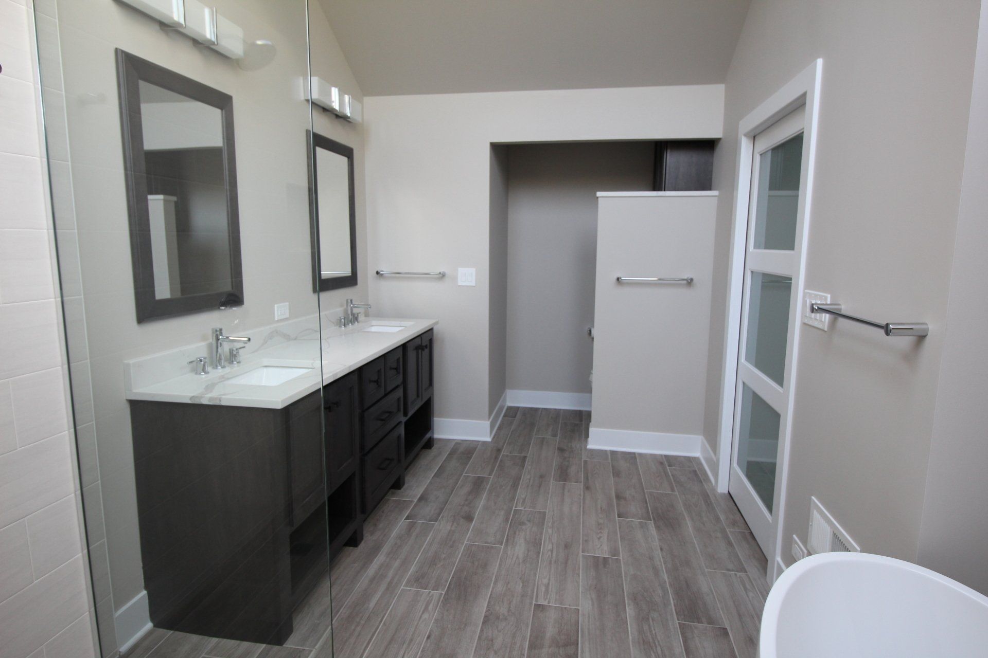 A bathroom with two sinks , two mirrors and a tub.