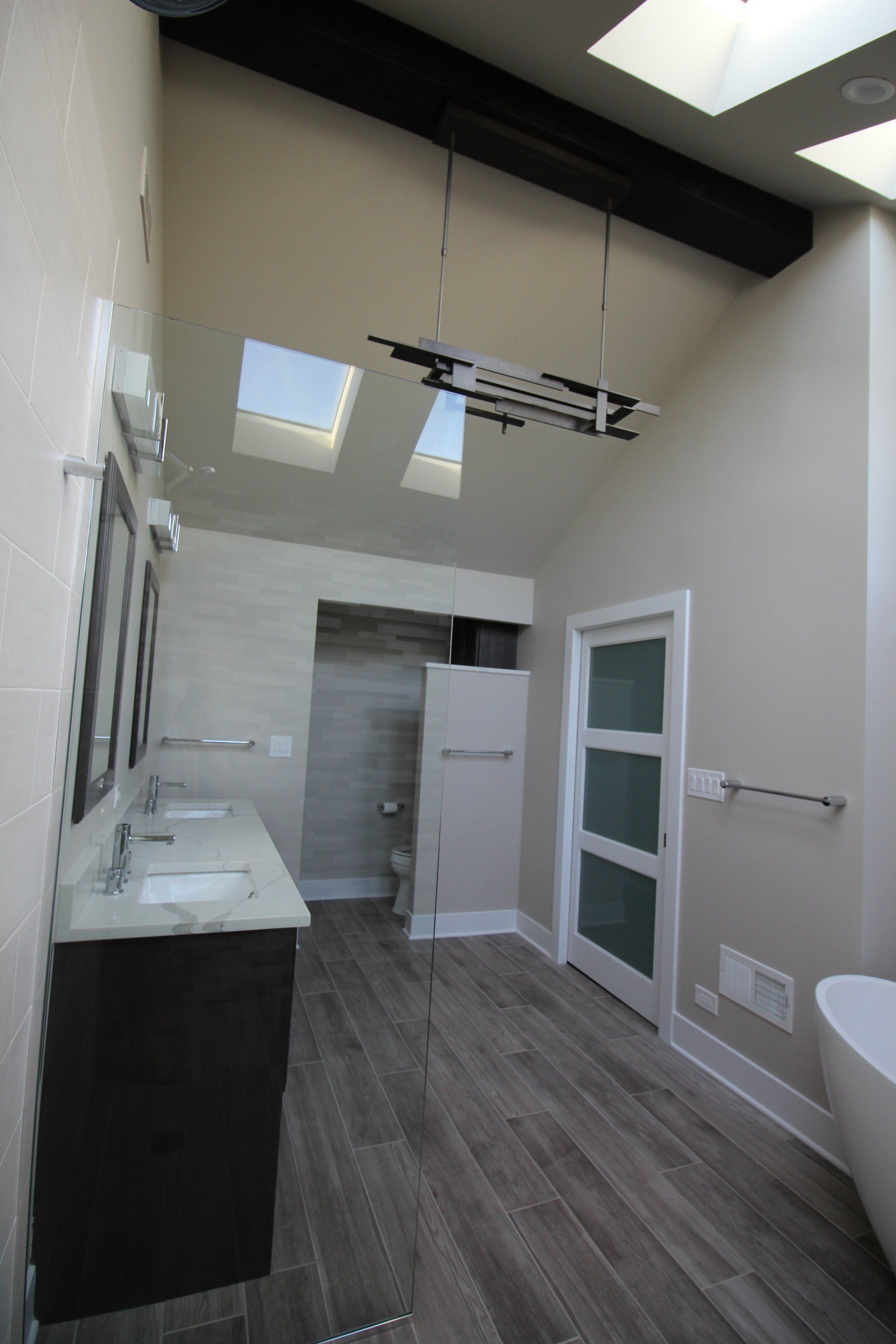 A bathroom with two sinks a toilet and a skylight