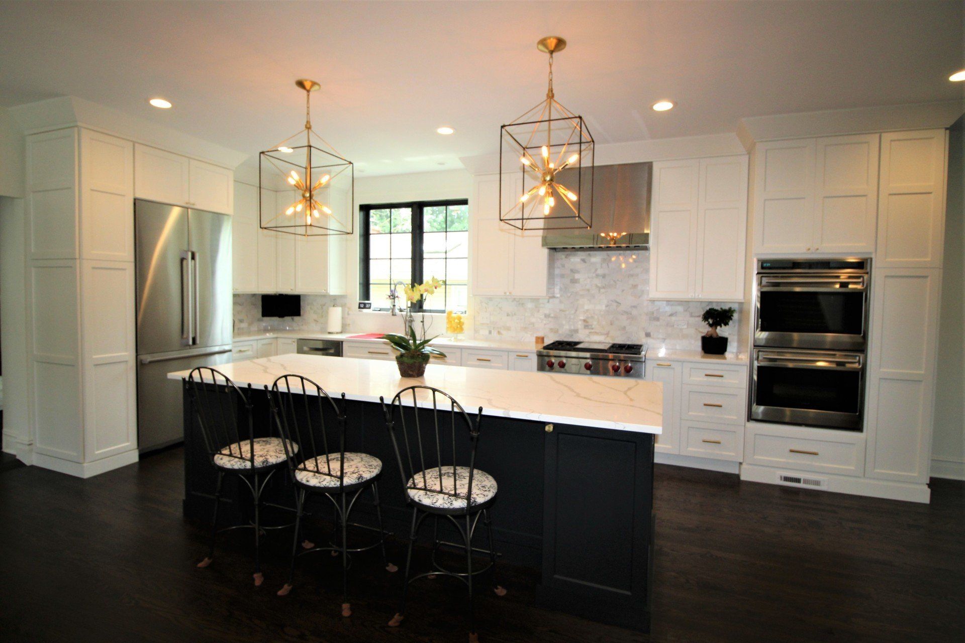 A kitchen with white cabinets , stainless steel appliances , and a large island.