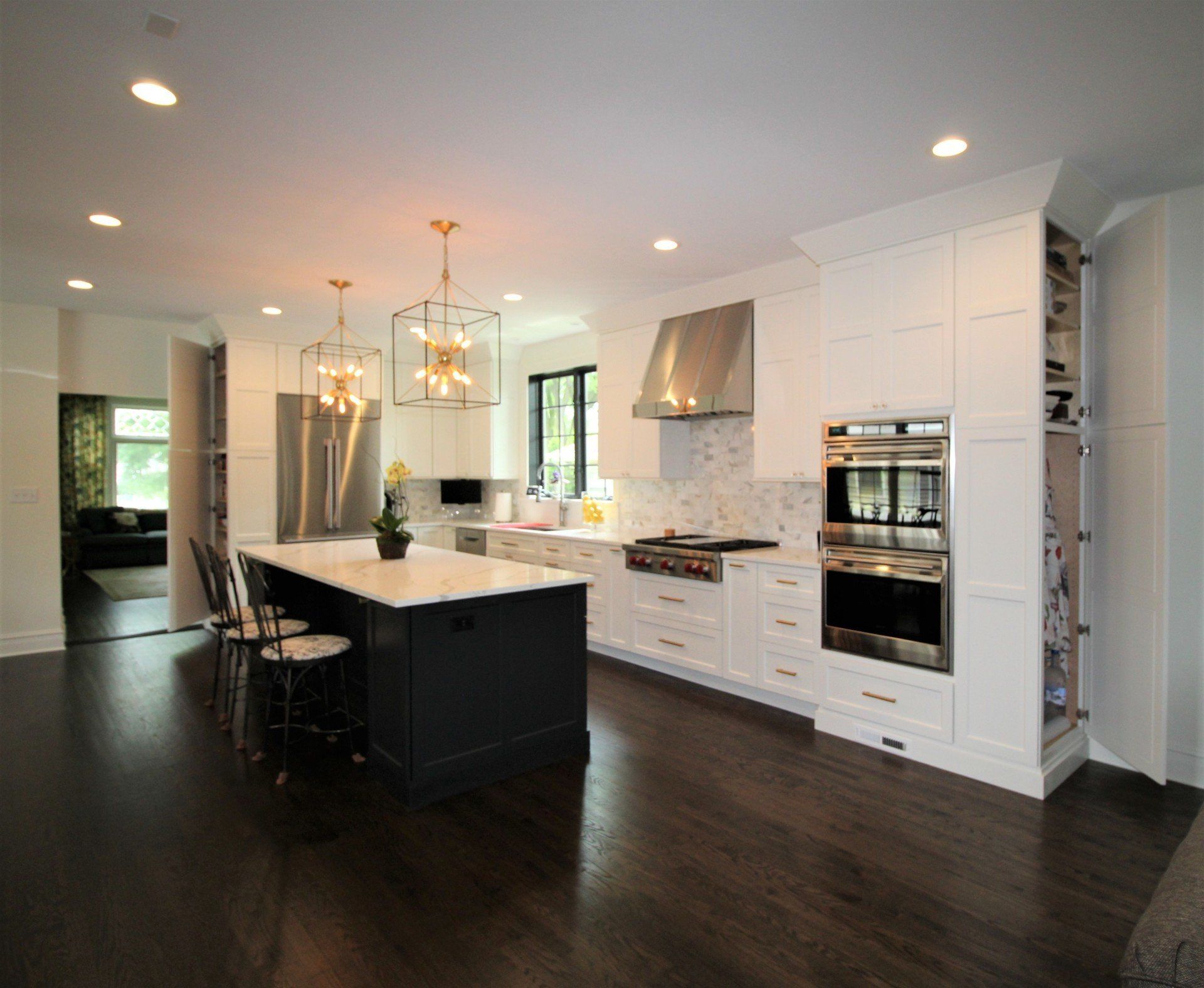 A kitchen with white cabinets and stainless steel appliances and a large island.