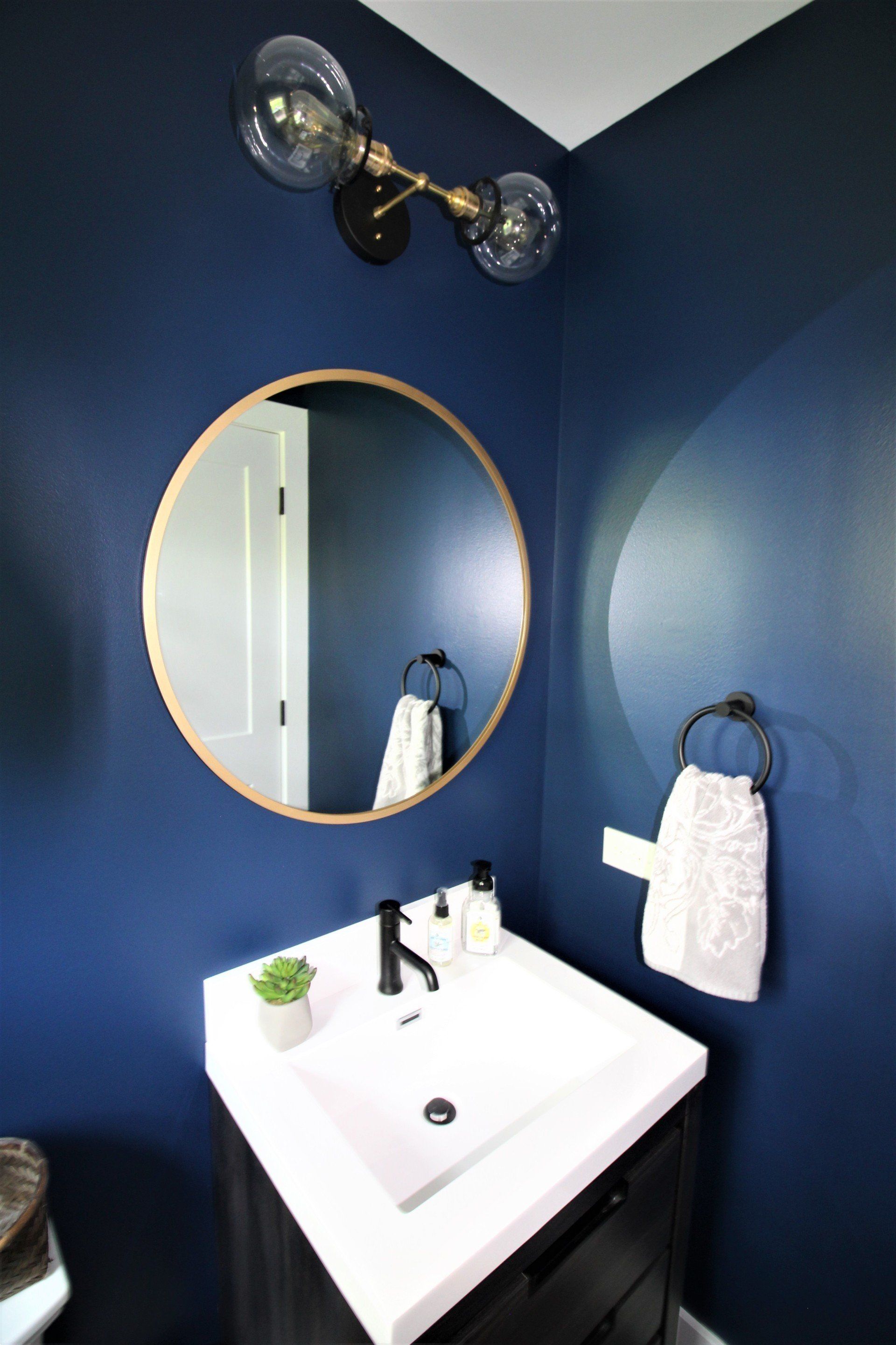 A bathroom with a sink , mirror and blue walls.