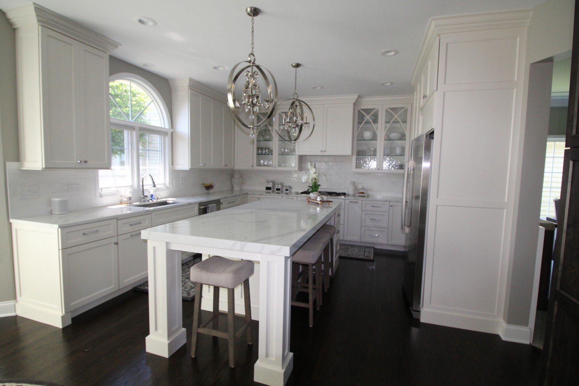 A kitchen with white cabinets and a large island in the middle.