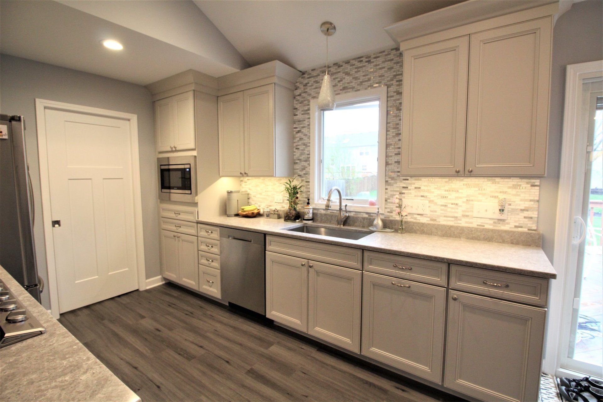A kitchen with white cabinets , stainless steel appliances , a sink , and a window.