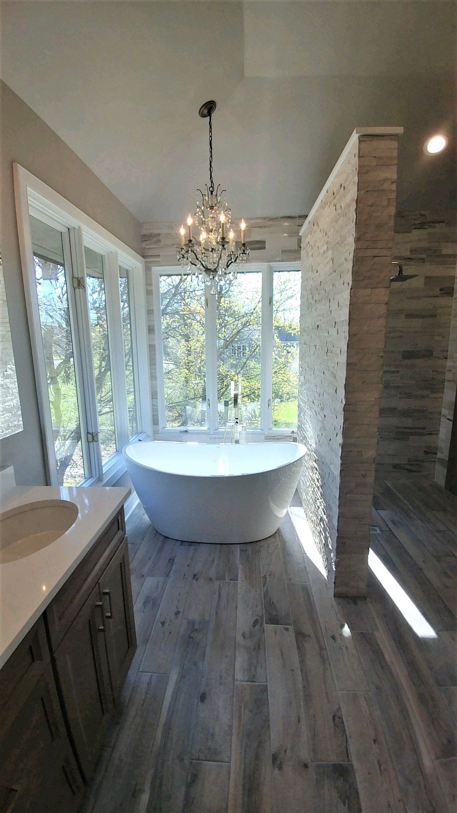 A bathroom with a tub , sink , and chandelier.