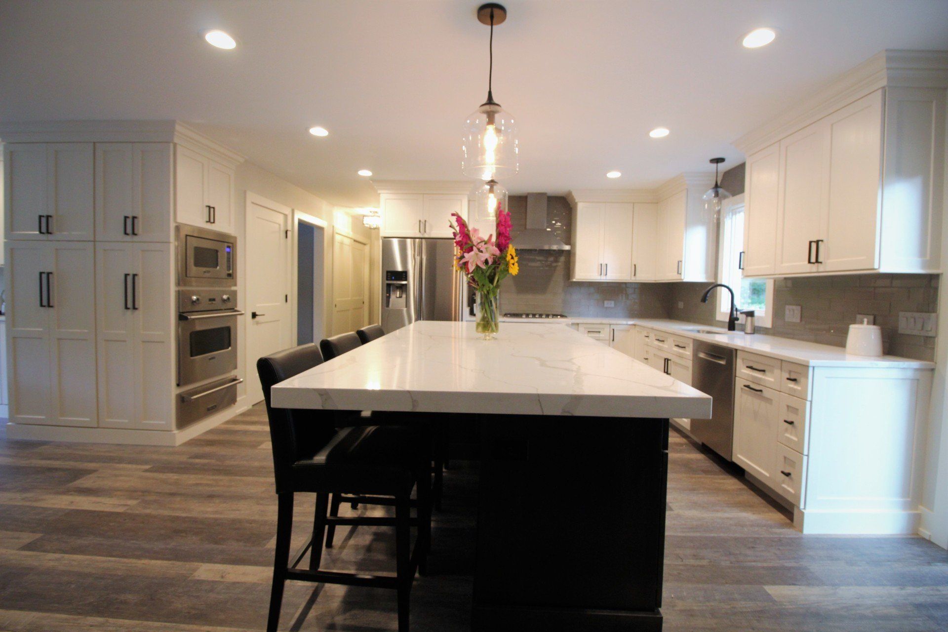 A kitchen with white cabinets and stainless steel appliances and a large island.