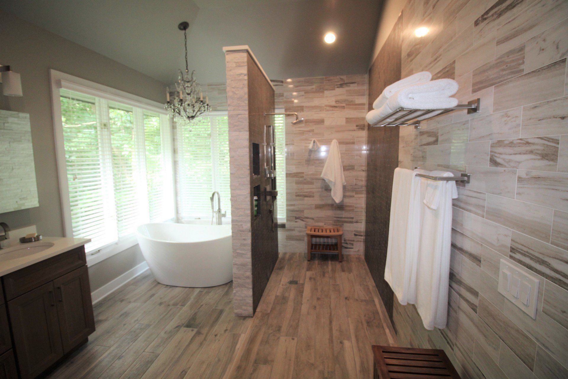 A bathroom with a tub , sink , mirror and towels.