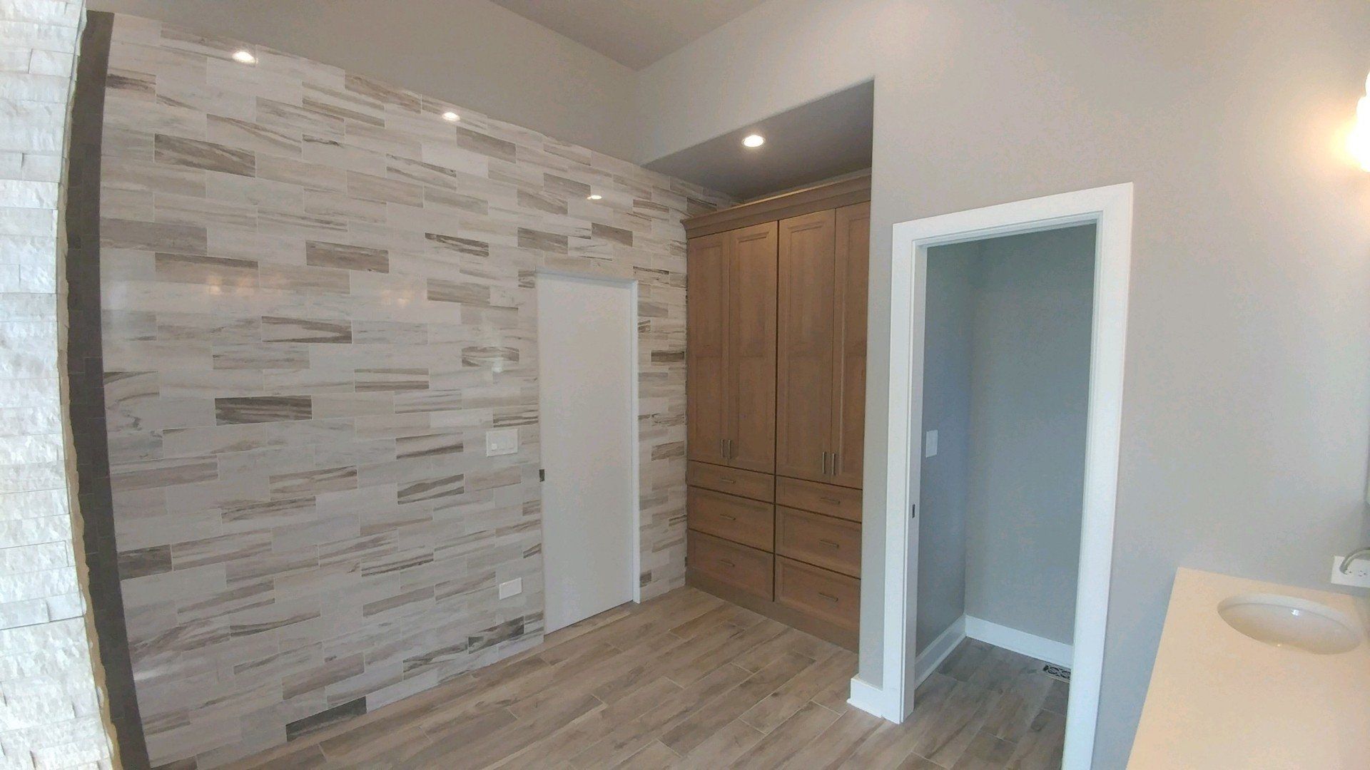 A bathroom with a walk in closet and a brick wall.