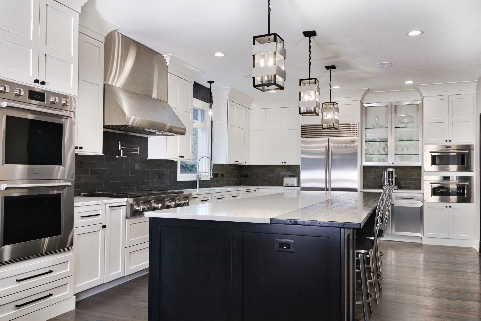A kitchen with white cabinets , stainless steel appliances , and a large island.