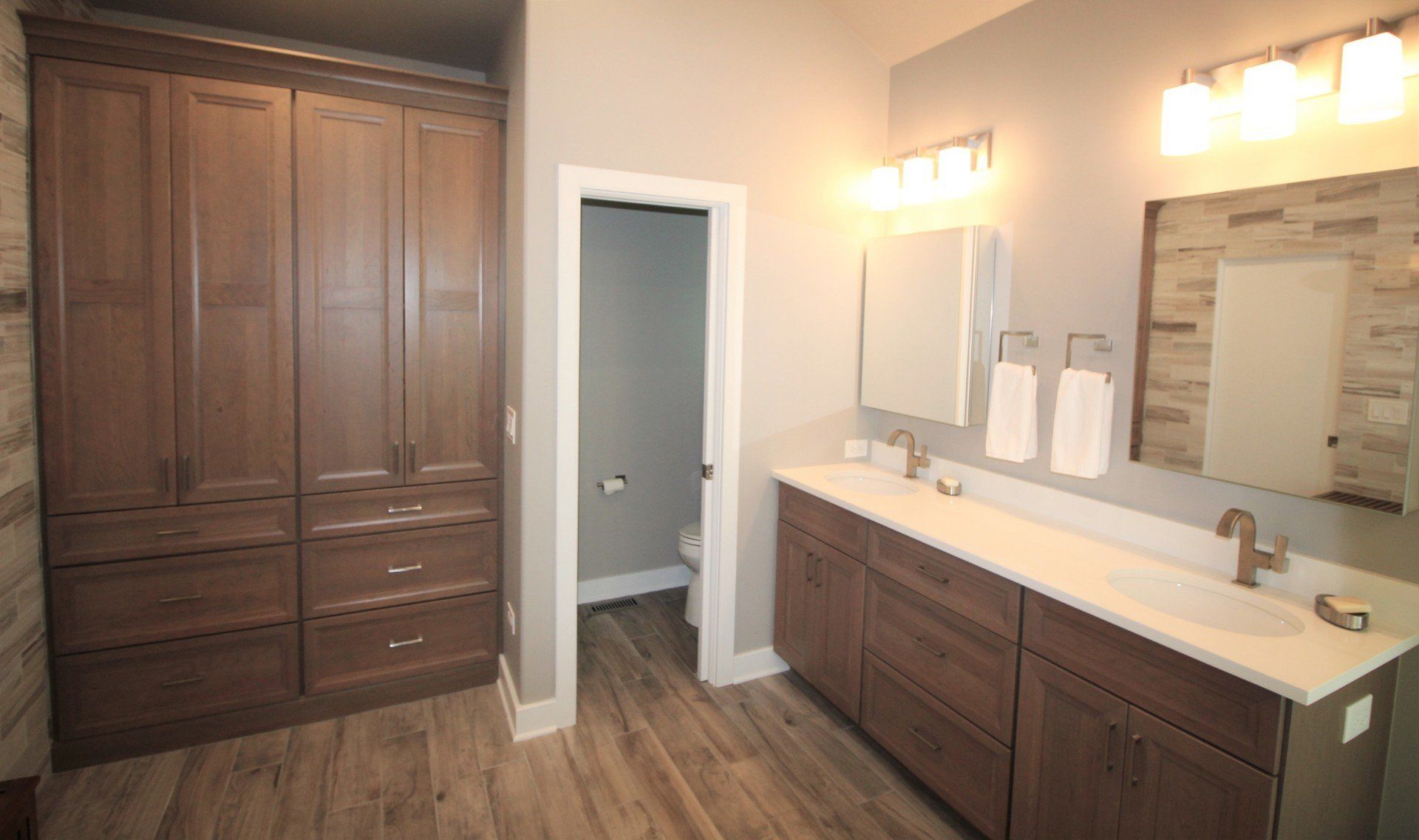 A bathroom with two sinks , a toilet and a mirror.