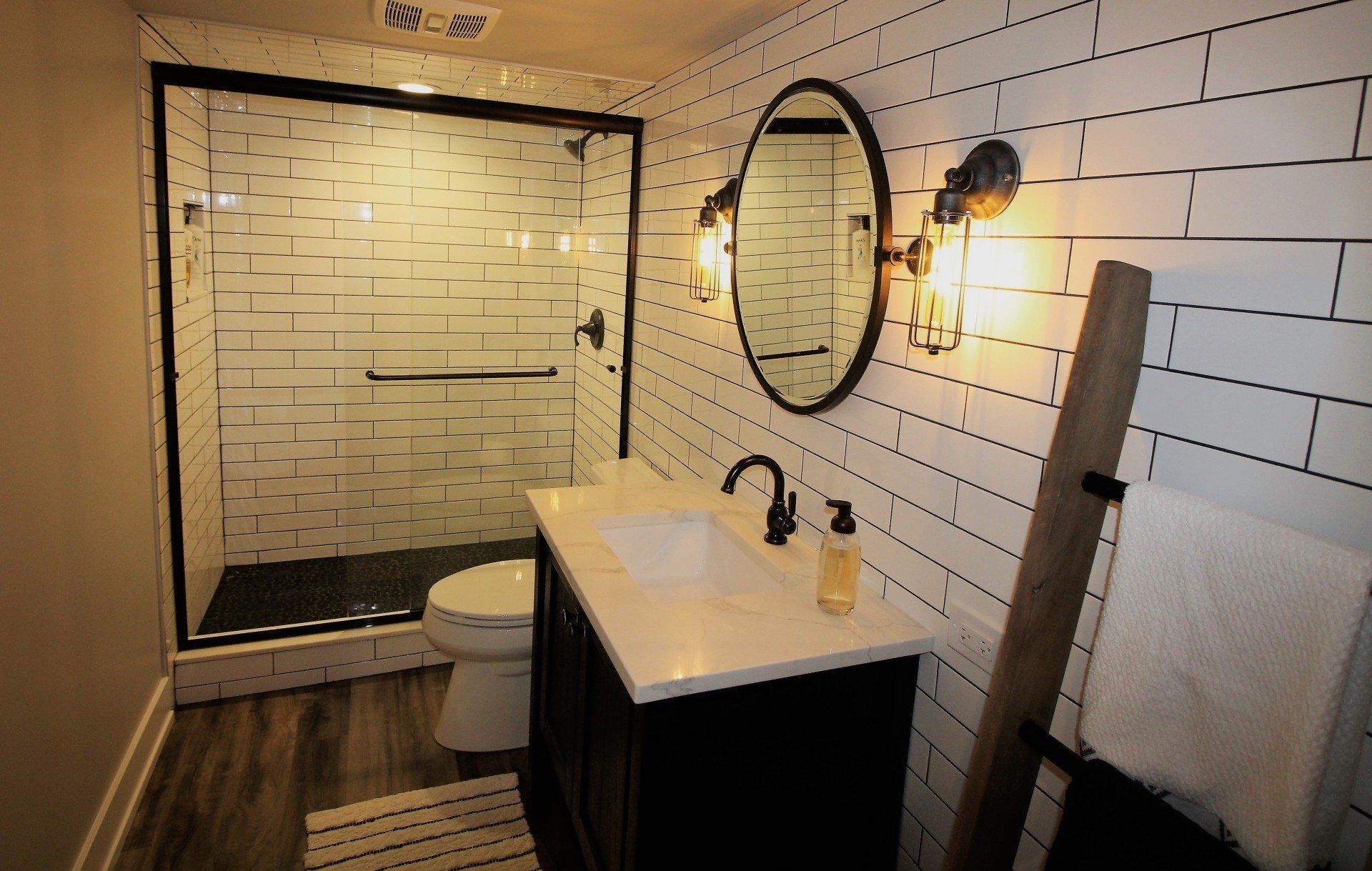 A bathroom with a sink , toilet , shower and mirror.