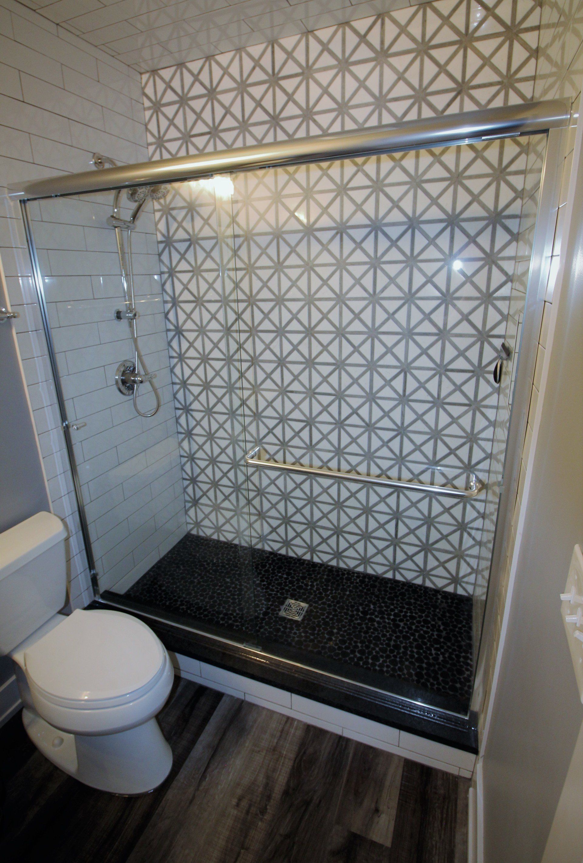 A bathroom with a toilet and a shower with a sliding glass door.